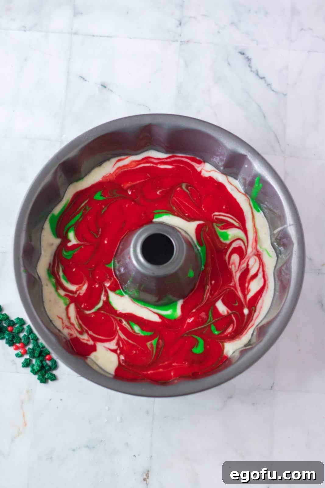 cake batter shown in a bundt pan with the red, white and green colors swirled together. 