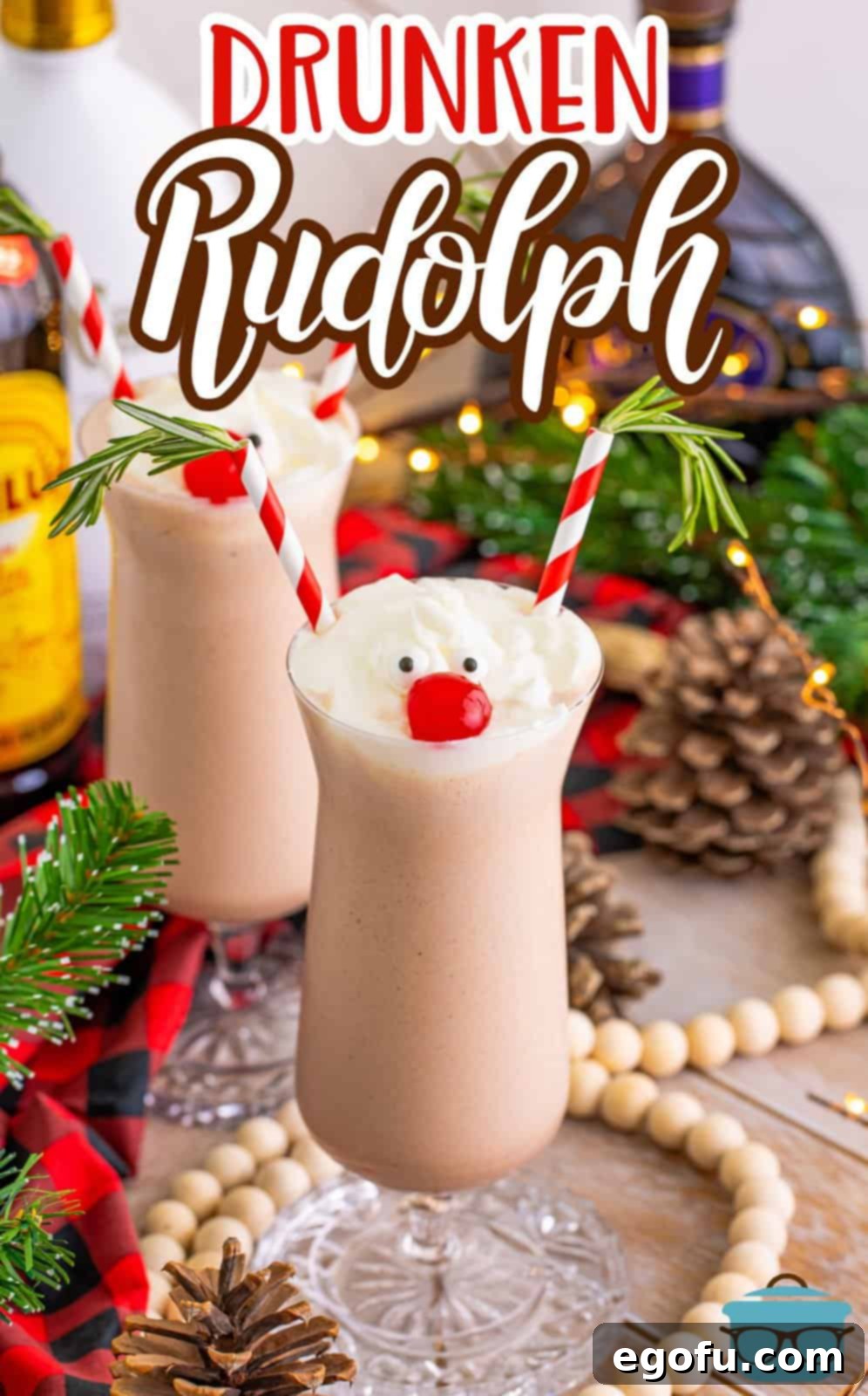 Rudolph on the Rocks 2 Two Drunken Rudolph milkshakes, garnished with candy eyes, a cherry nose, and straw antlers, surrounded by festive Christmas decorations.