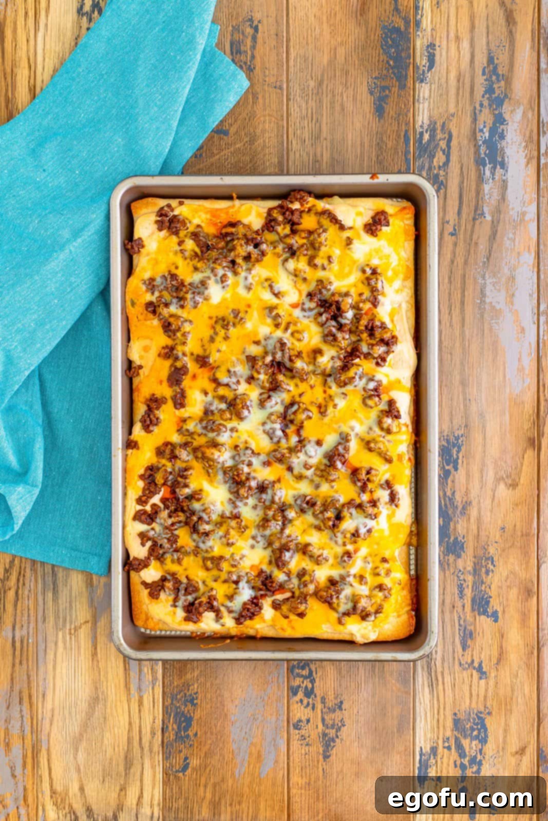 A fully baked taco pizza, without fresh toppings, fresh out of the oven with melted, bubbly cheese and a golden crust.