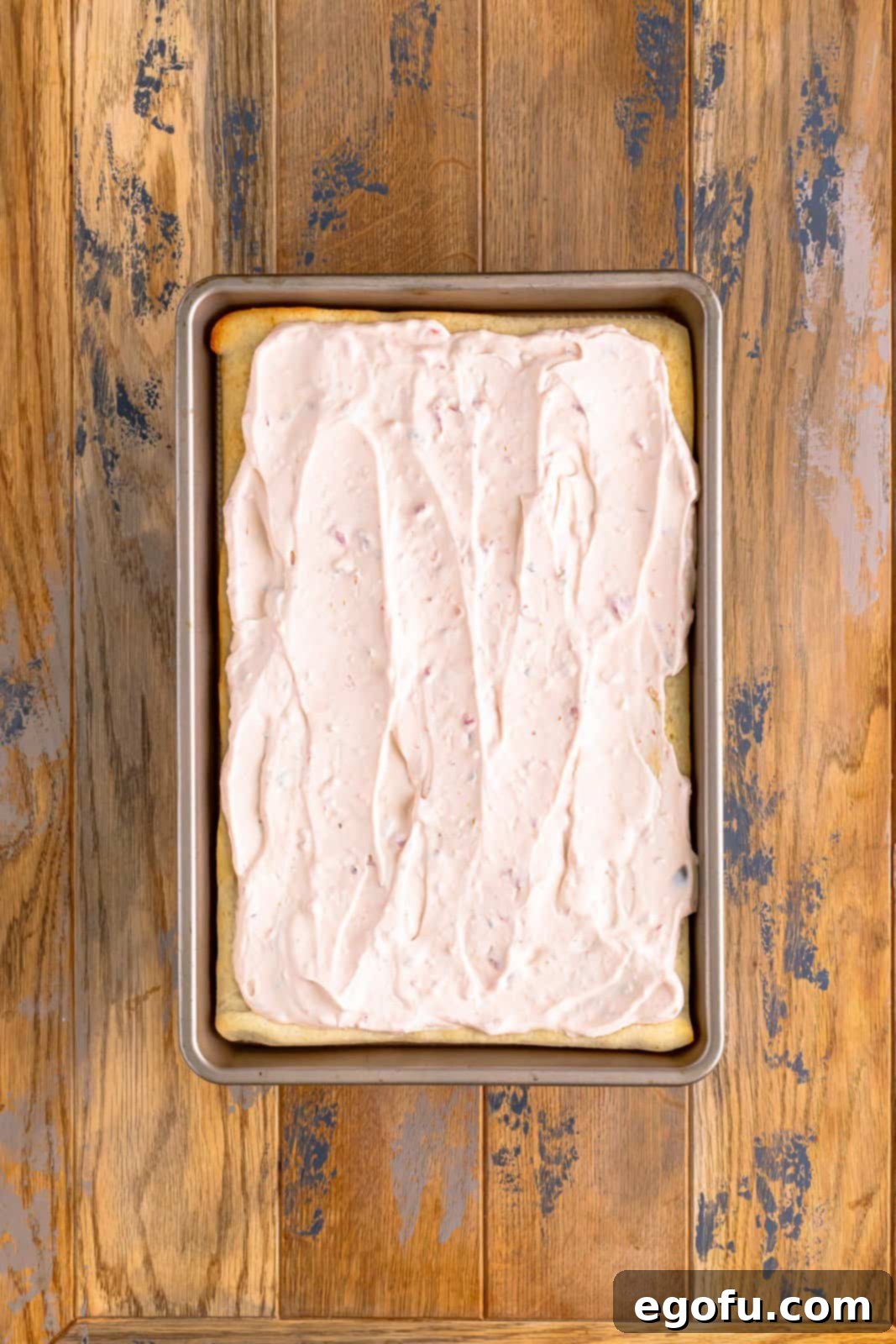 A creamy salsa cream cheese mixture spread out evenly onto a parbaked pizza crust, leaving a small border.