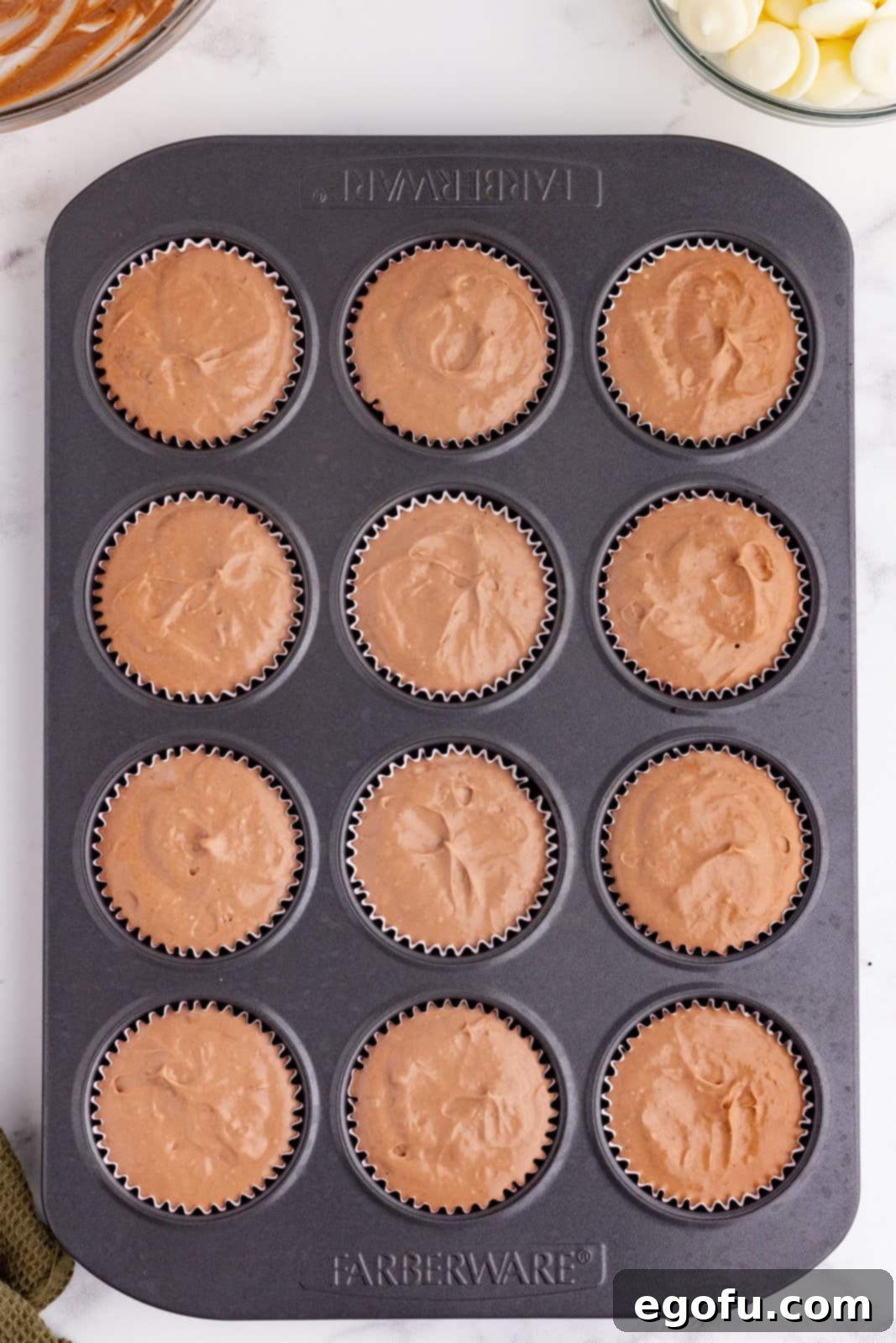 chocolate cheesecake batter added to cupcakes liners in baking pan. 