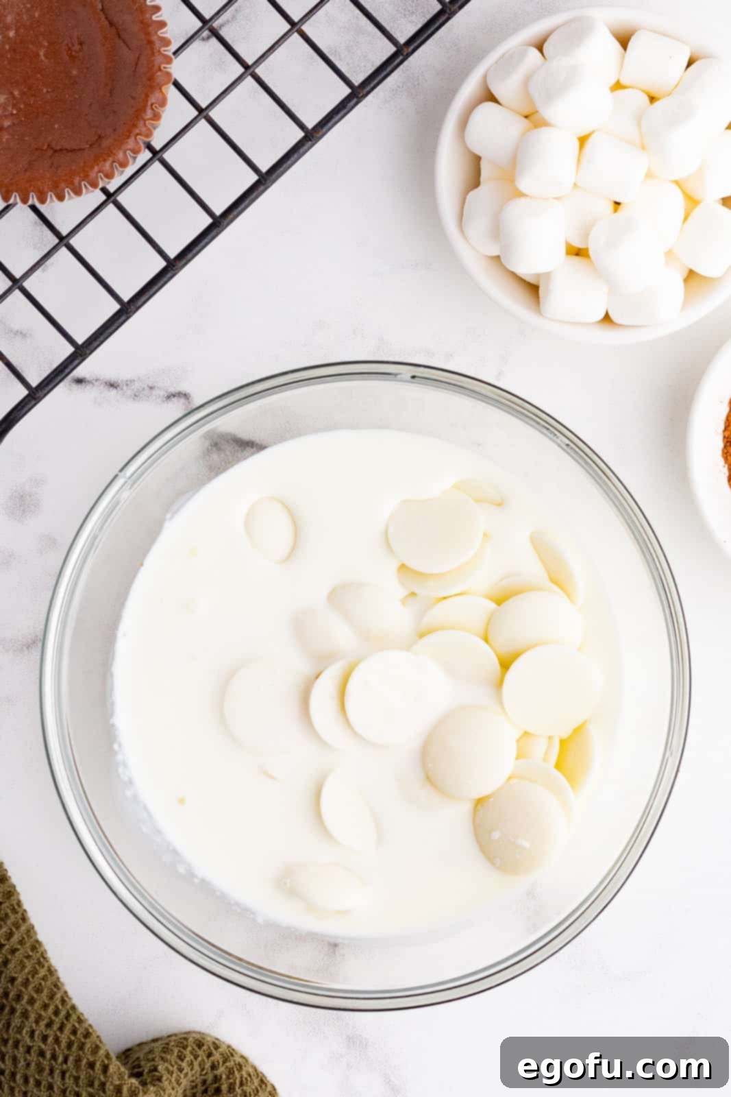 white chocolate wafers and heavy cream in a clear bowl. 