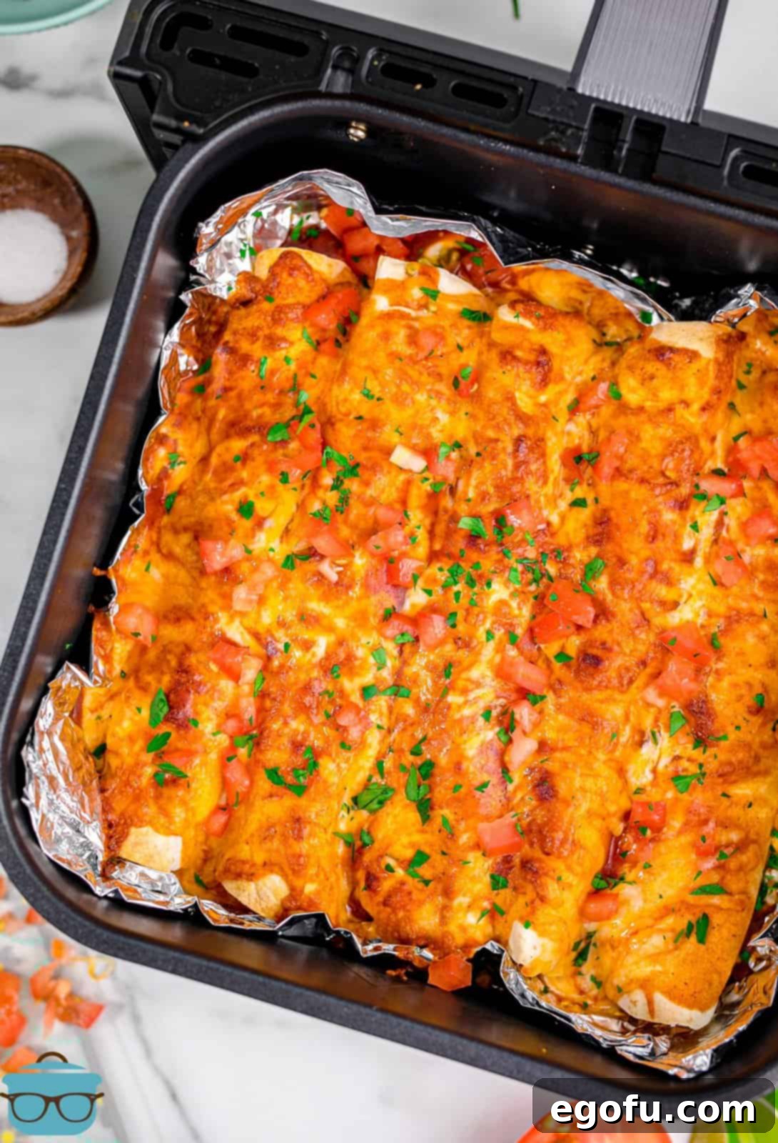 fully cooked chicken enchiladas shown in air fryer basket.
