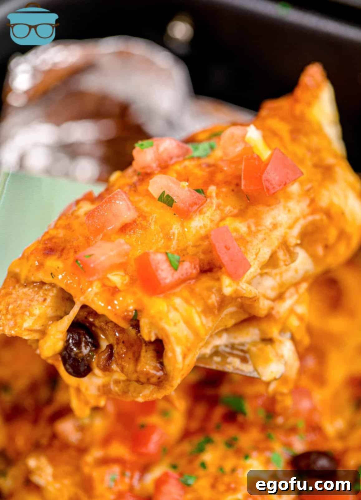 a spatula lifting up one of the chicken enchiladas out of the air fryer.