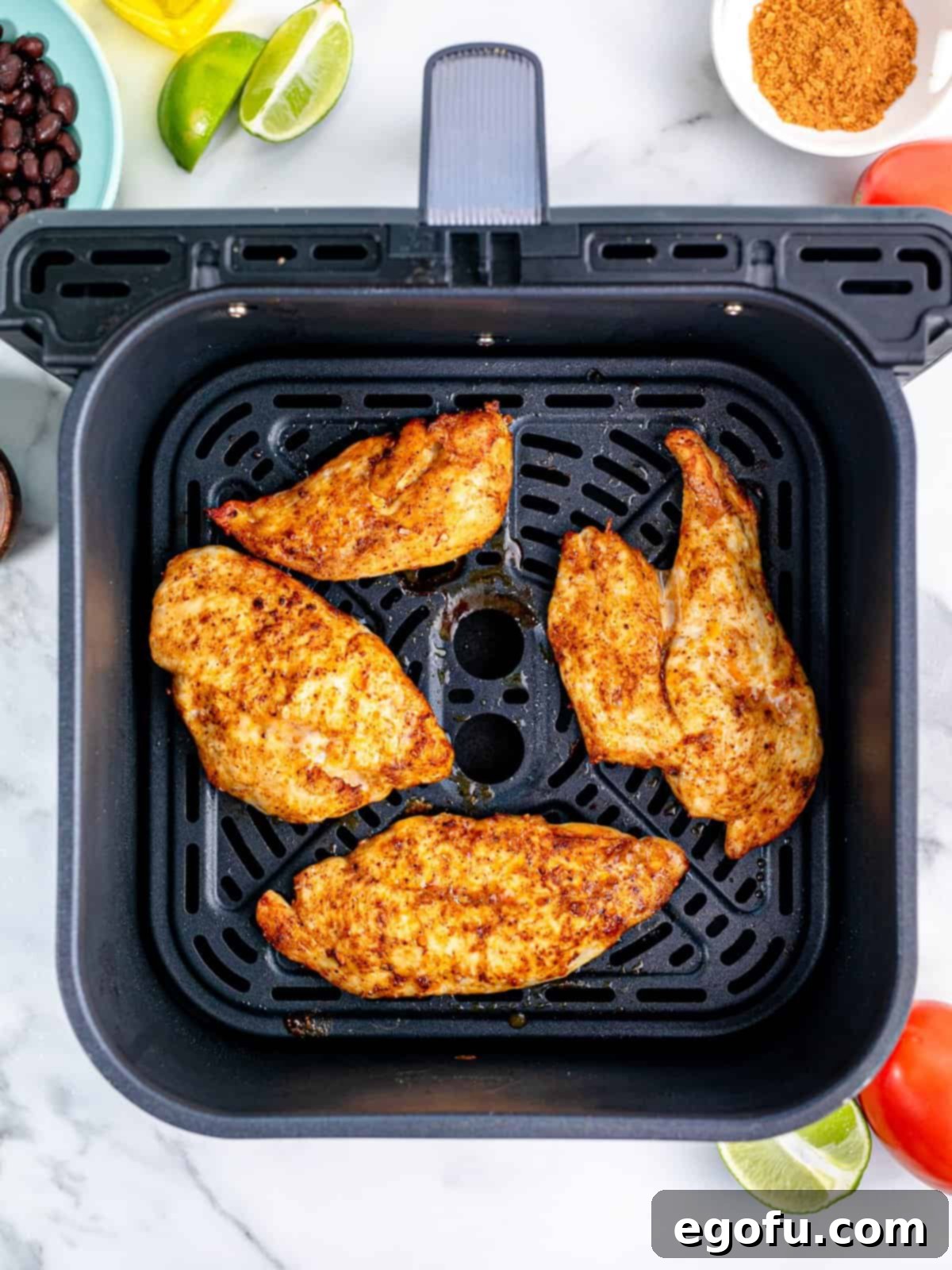 fully cooked chicken breasts shown in an air fryer basket.