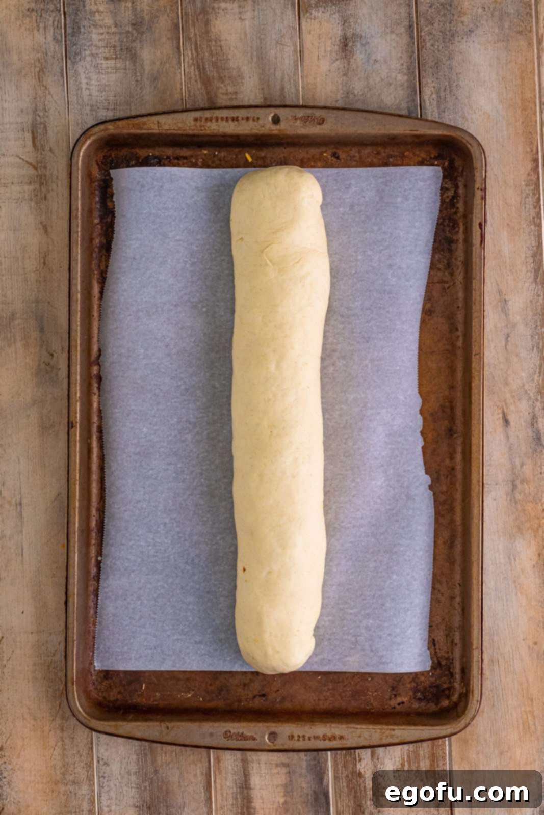 Effortless Ham and Cheese Stromboli Delight 13 rolled up stuffed pizza dough on parchment paper lined baking sheet.