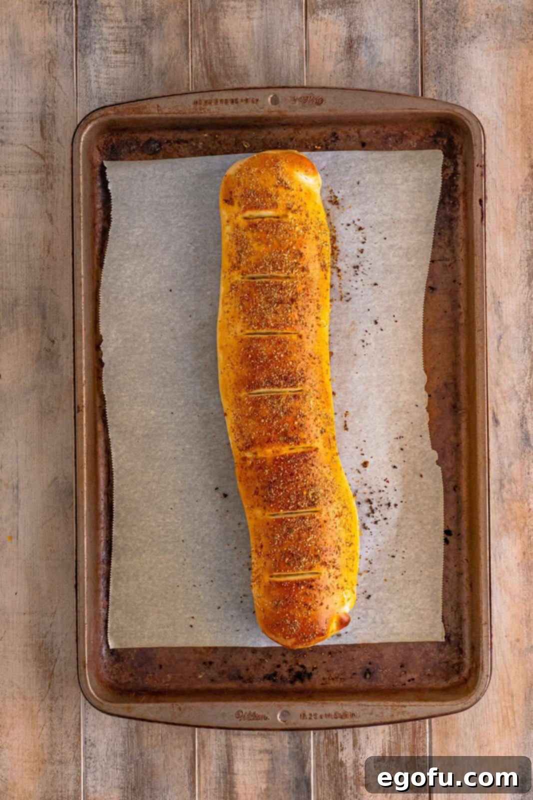 Effortless Ham and Cheese Stromboli Delight 17 fully baked ham and cheese Stromboli on a parchment paper lined baking sheet.