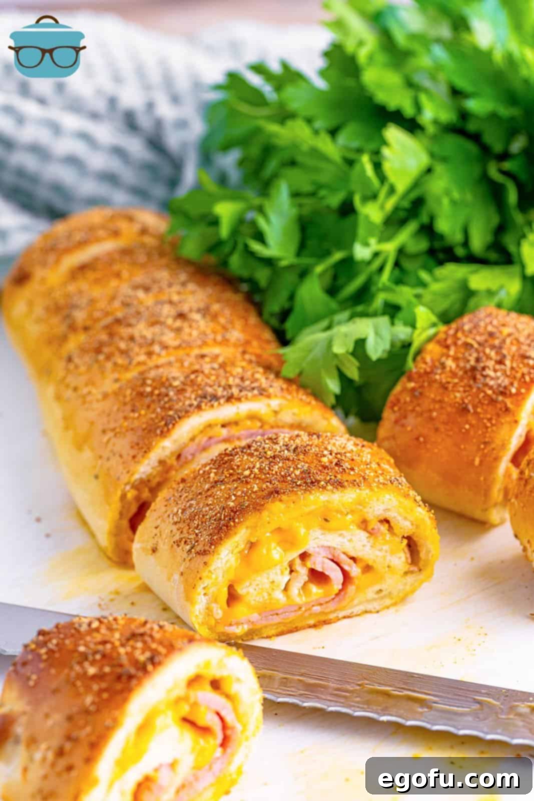 Effortless Ham and Cheese Stromboli Delight 18 ham and cheese Stromboli being cut into slices on a cutting board.