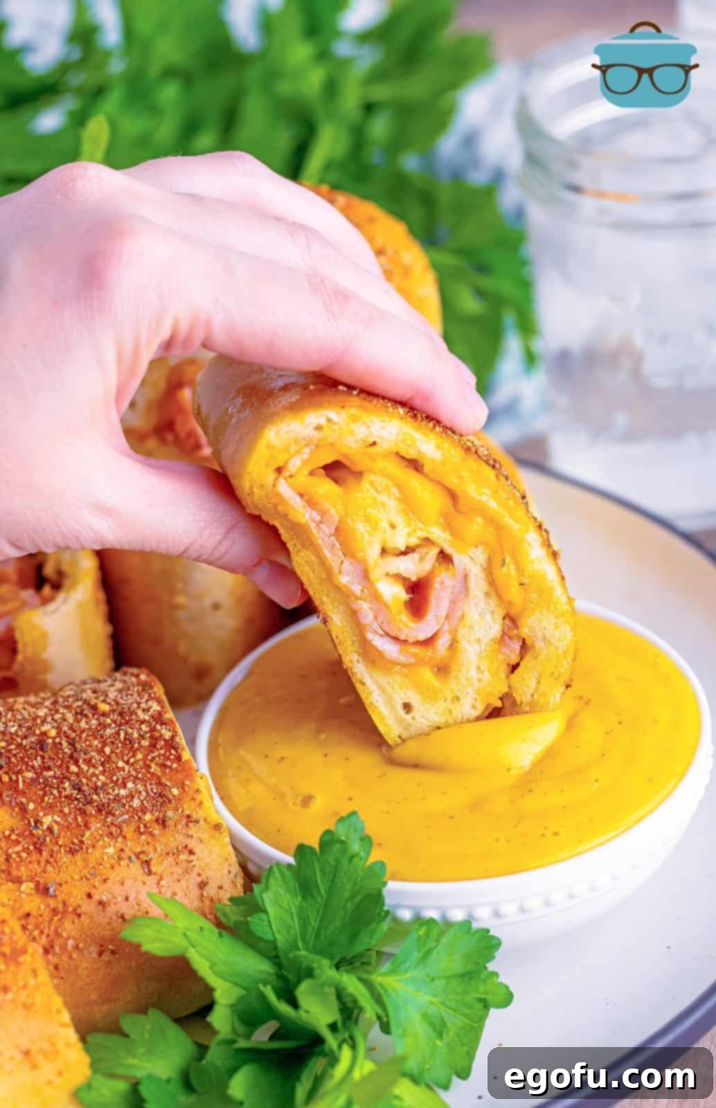 Effortless Ham and Cheese Stromboli Delight 19 a hand holding a slice of ham and cheese Stromboli and dipping it into honey mustard sauce.