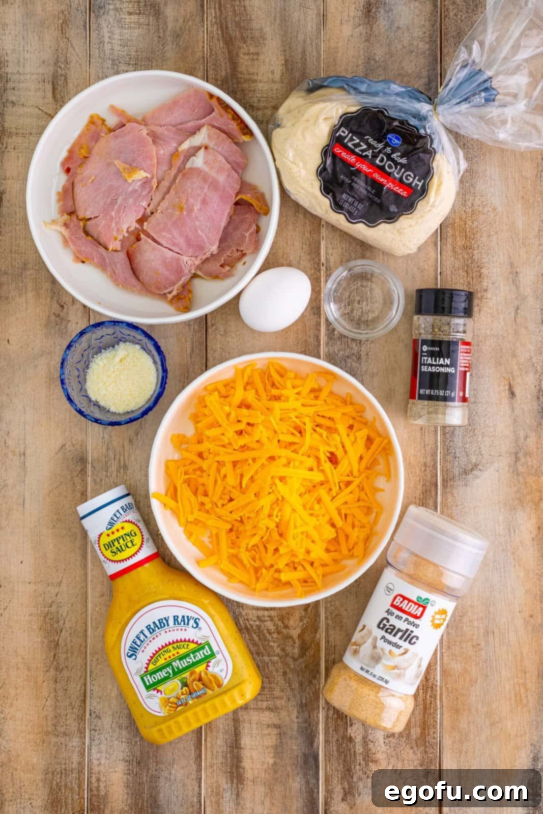 Effortless Ham and Cheese Stromboli Delight 4 pizza dough, parmesan cheese, garlic powder, Italian seasoning, sharp cheddar cheese, leftover sliced ham and egg.