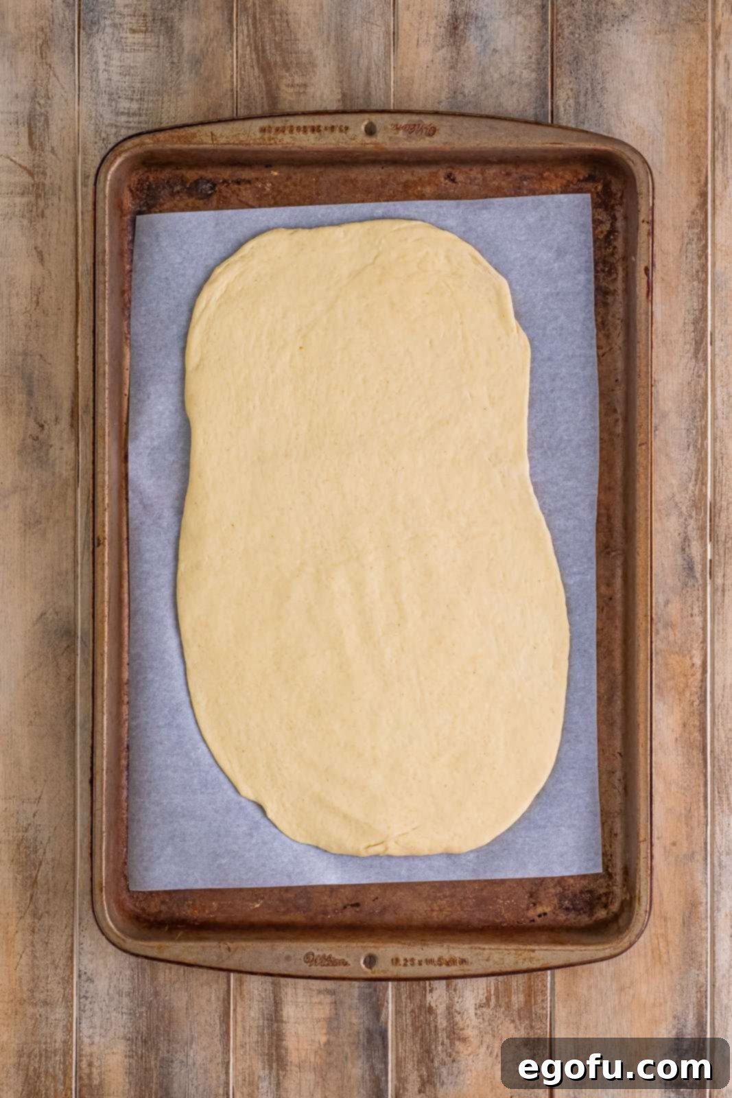 Effortless Ham and Cheese Stromboli Delight 6 pizza dough spread out on a parchment paper lined baking sheet.