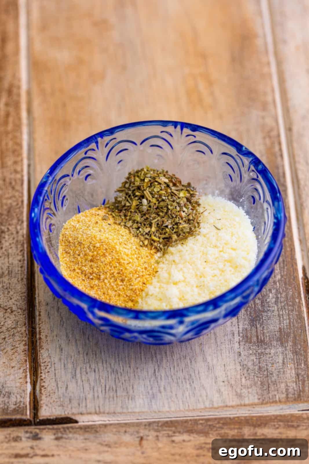 Effortless Ham and Cheese Stromboli Delight 7 parmesan cheese, garlic powder and Italian seasoning in a small blue bowl.