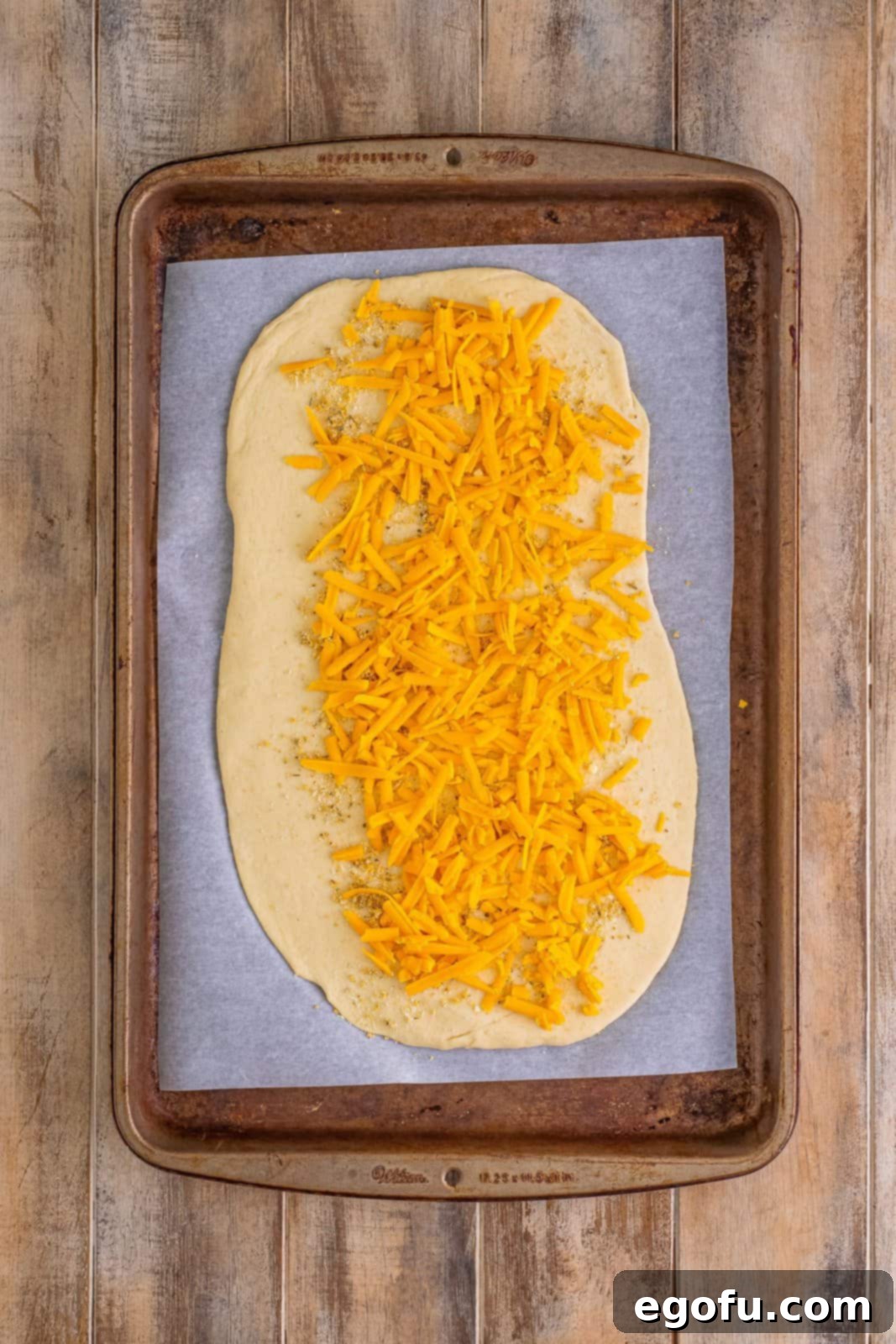 Effortless Ham and Cheese Stromboli Delight 9 shredded cheddar cheese sprinkled on top of pizza dough.