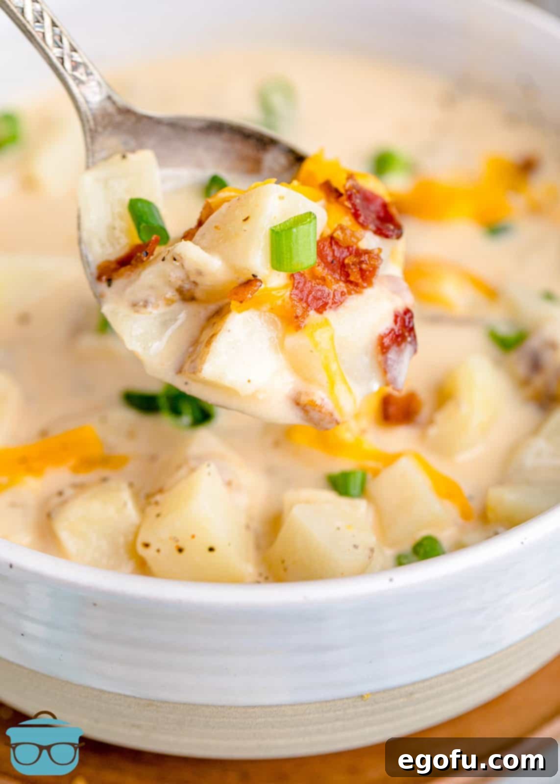 Effortless Slow Cooker Potato Soup with Frozen Potatoes 2 A spoonful of rich, creamy slow cooker potato soup being lifted from a bowl filled with the comforting dish.