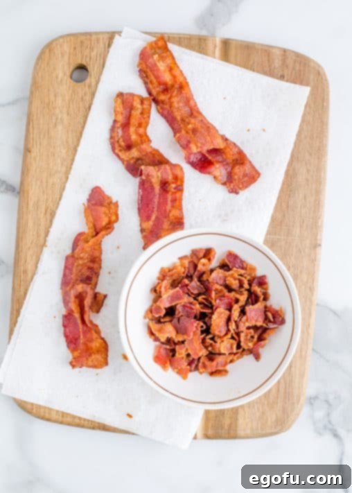 Effortless Slow Cooker Potato Soup with Frozen Potatoes 12 cooked bacon shown on a paper towel with some of the bacon shown crumbled in a bowl.