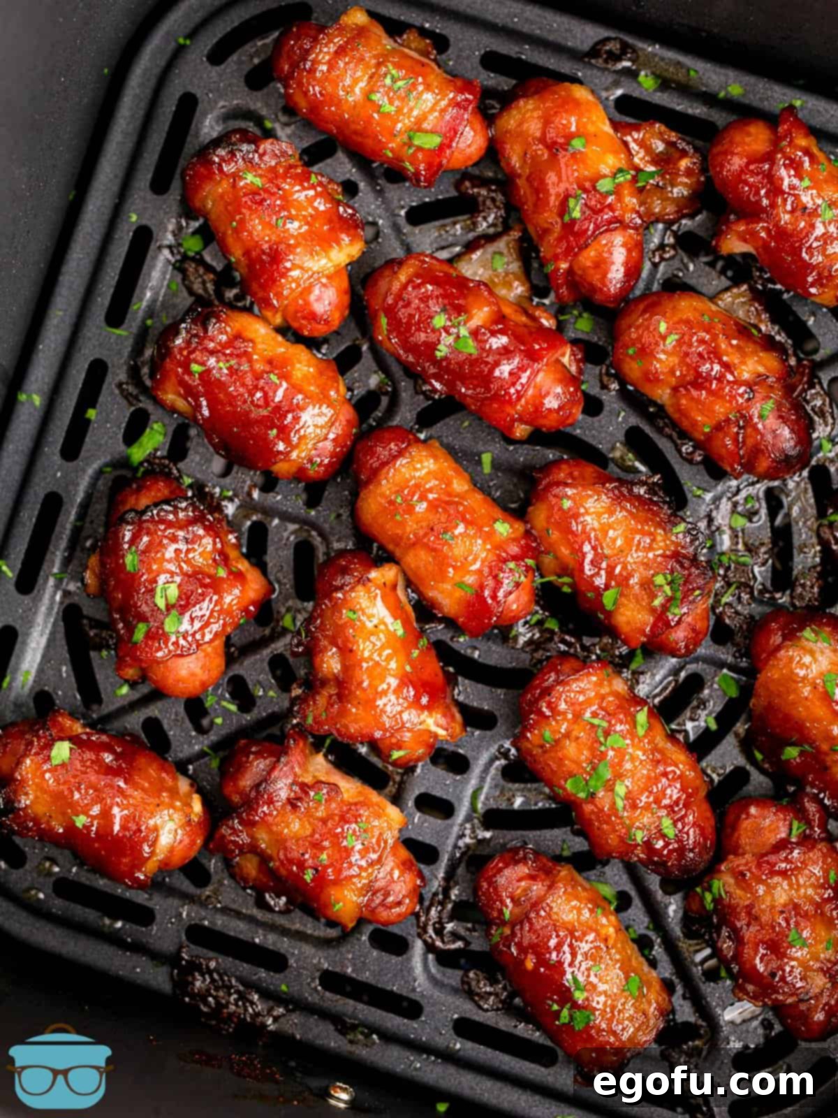 closeup shot of the cooked bacon wrapped little smokies in the air fryer basket.