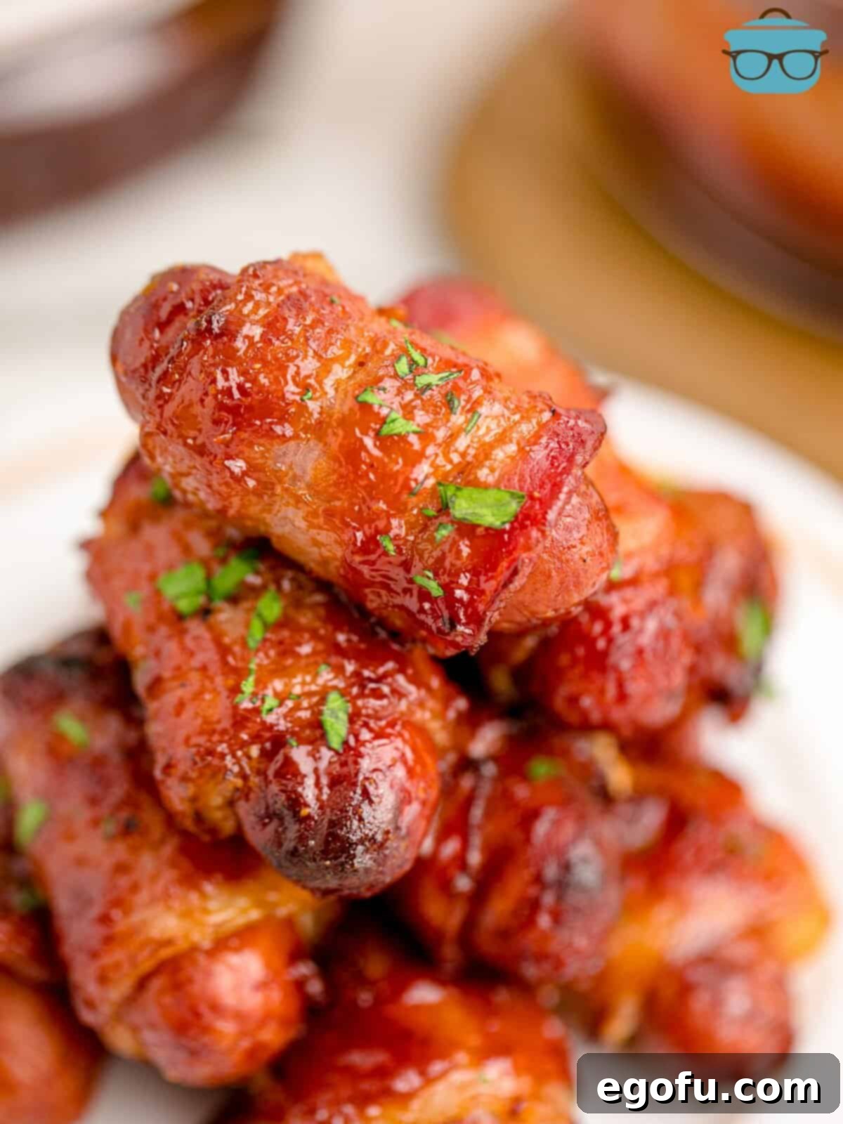 fully cooked bacon wrapped lit'l smokes shown stacked on a white plate.