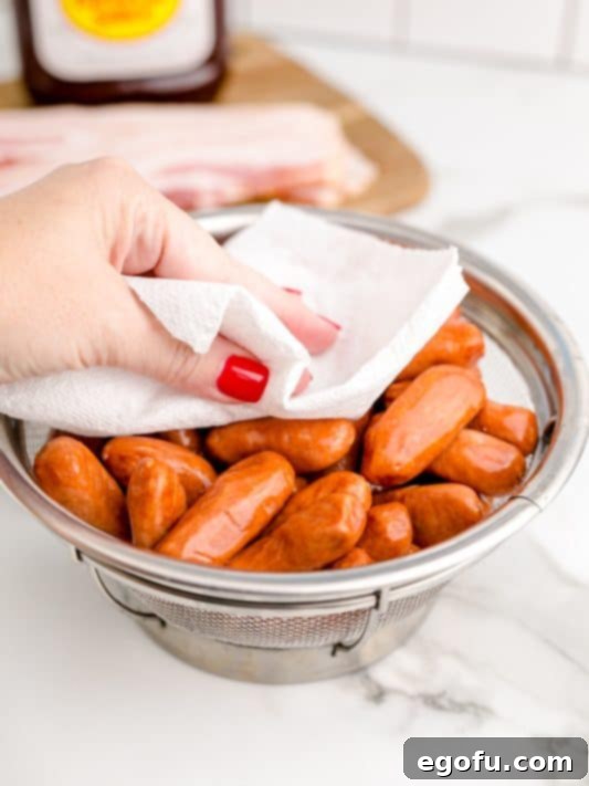 patting cocktail sausages dry with a paper towel.