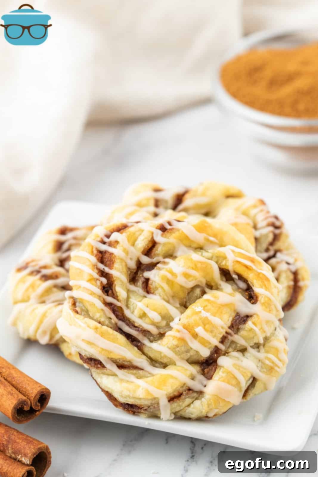 three cinnamon knots shown stacked on a square white plate. 