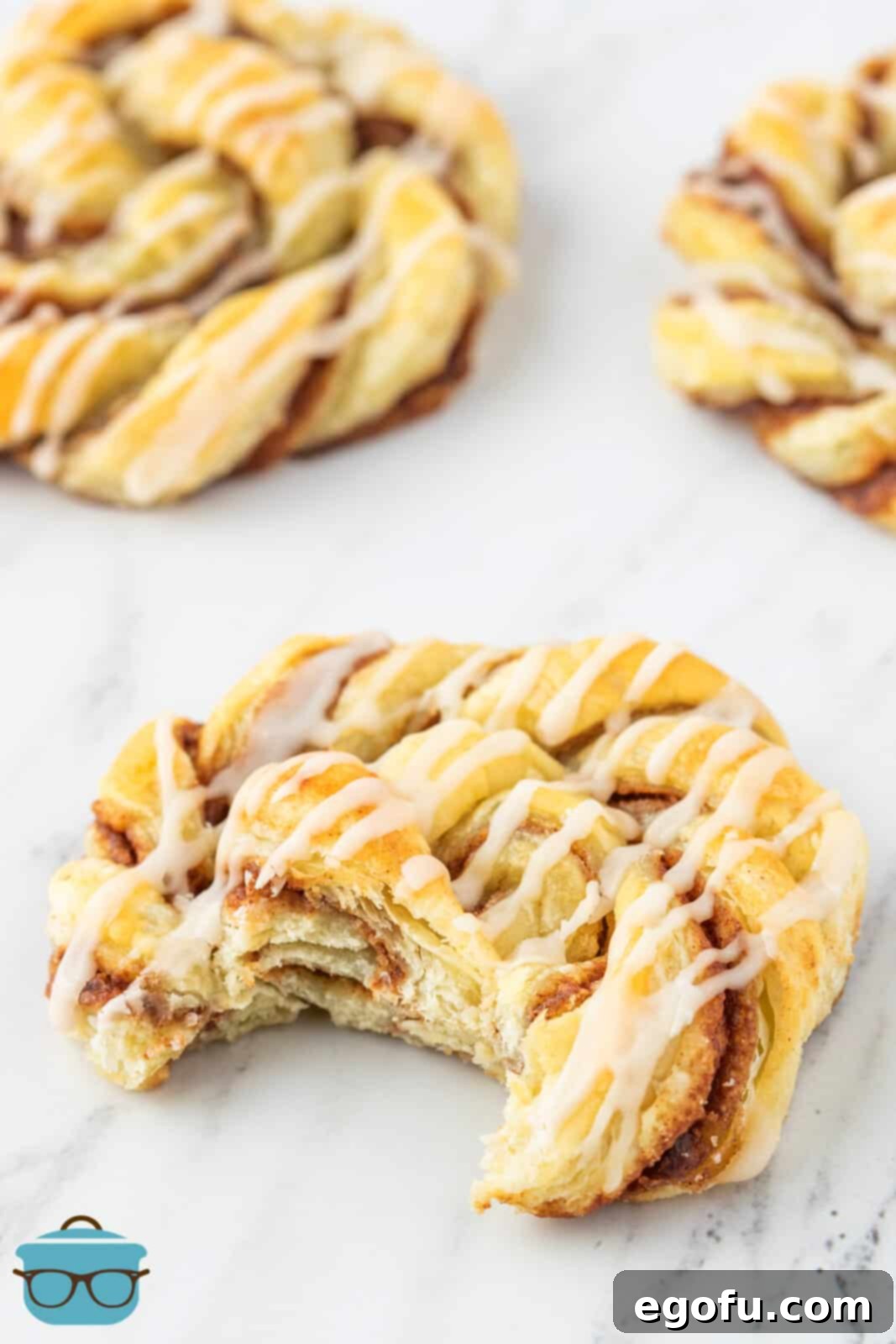 cinnamon knots shown on a marble surface with a bite removed from one of the cinnamon knots. 