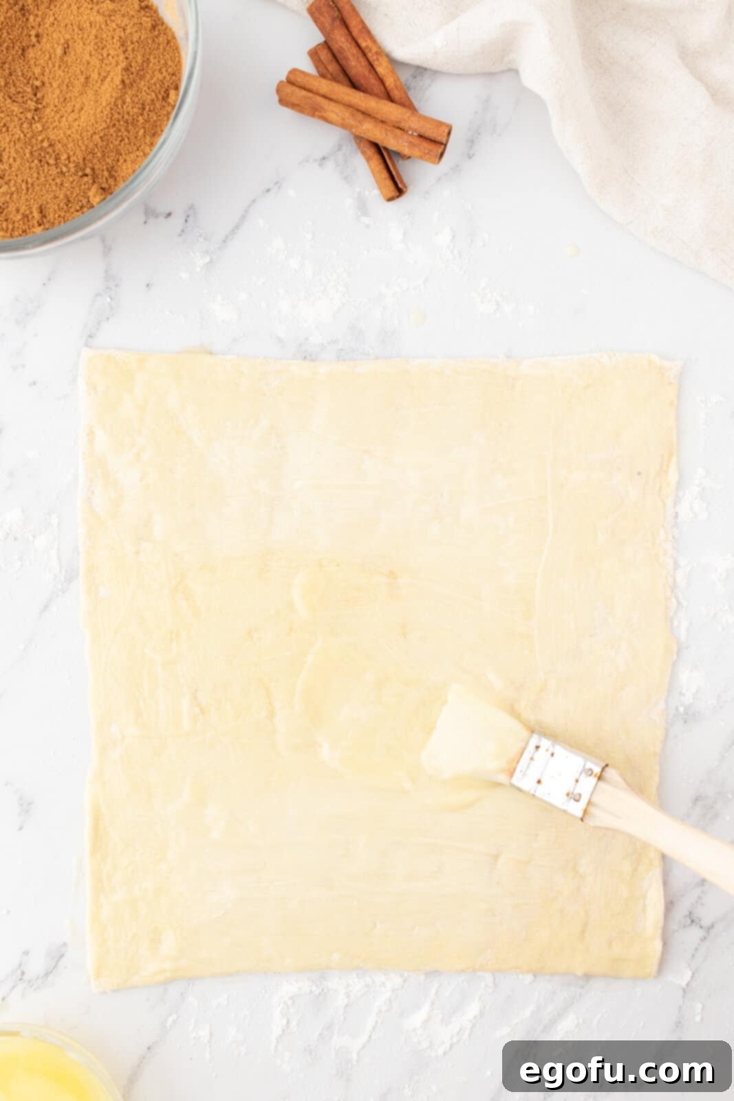 brushing a sheet of puff pastry with melted butter. 