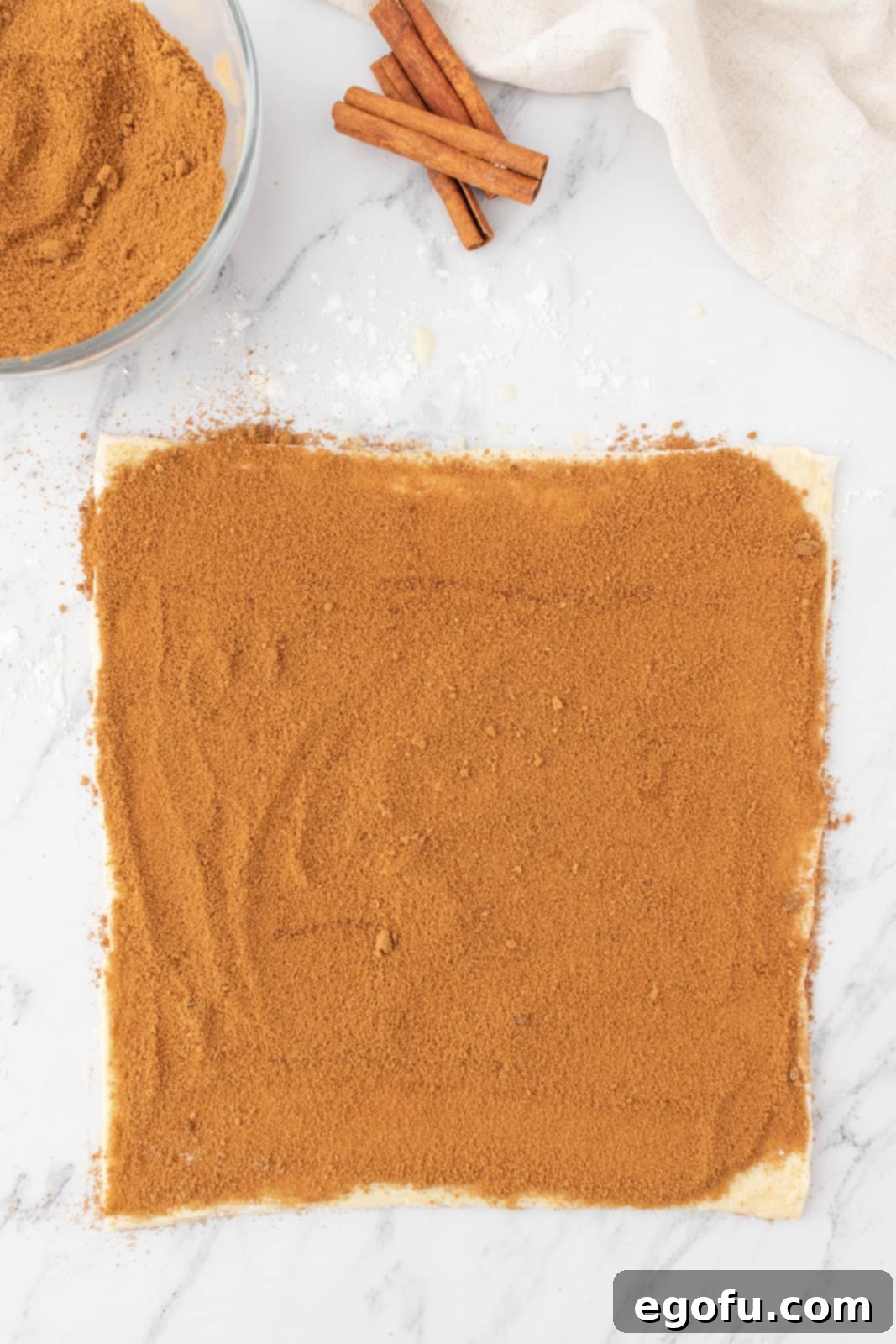 cinnamon sugar mixture evenly sprinkled on top of puff pastry dough sheet. 
