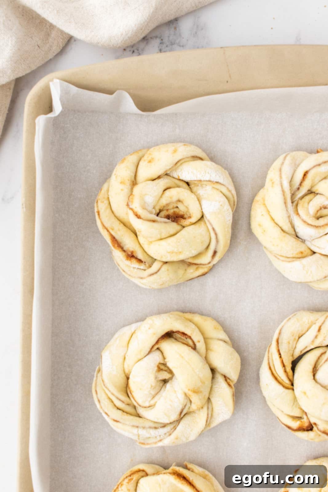 rolled up puff pastry shaped into a knot on a parchment paper lined baking sheet. 