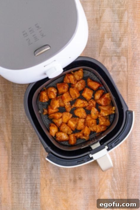 seasoned chicken breasts in a single layer shown in an air fryer basket.