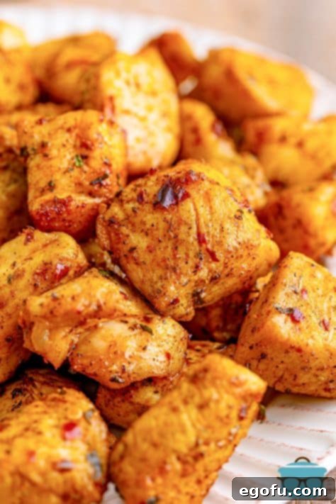 close up photo of chicken bites stacked up on a white plate.