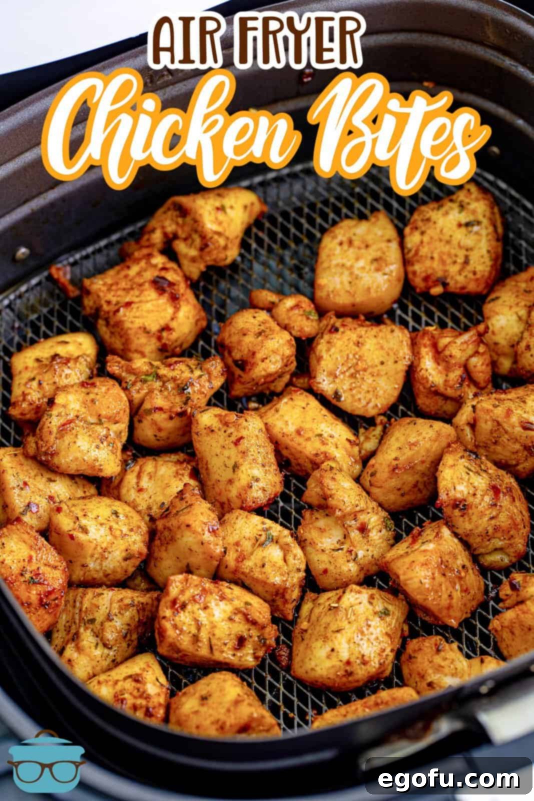 A close-up view of fully cooked and perfectly seasoned chicken breast bites arranged neatly in a black air fryer basket, showcasing their golden-brown exterior and delicious texture.