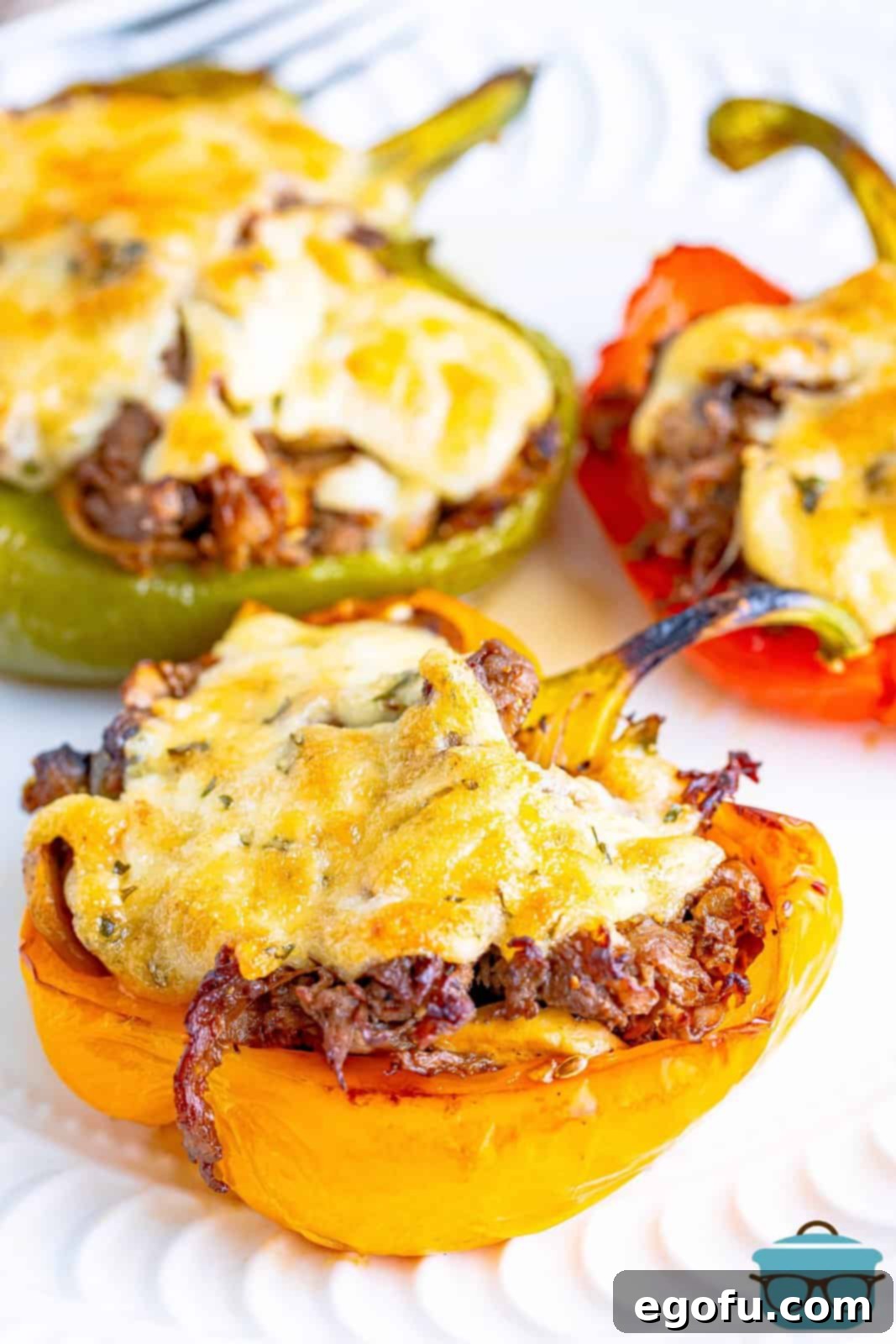 Philly Cheesesteak Pepper Boats 2 three cheesesteak stuffed peppers on a white round plate.