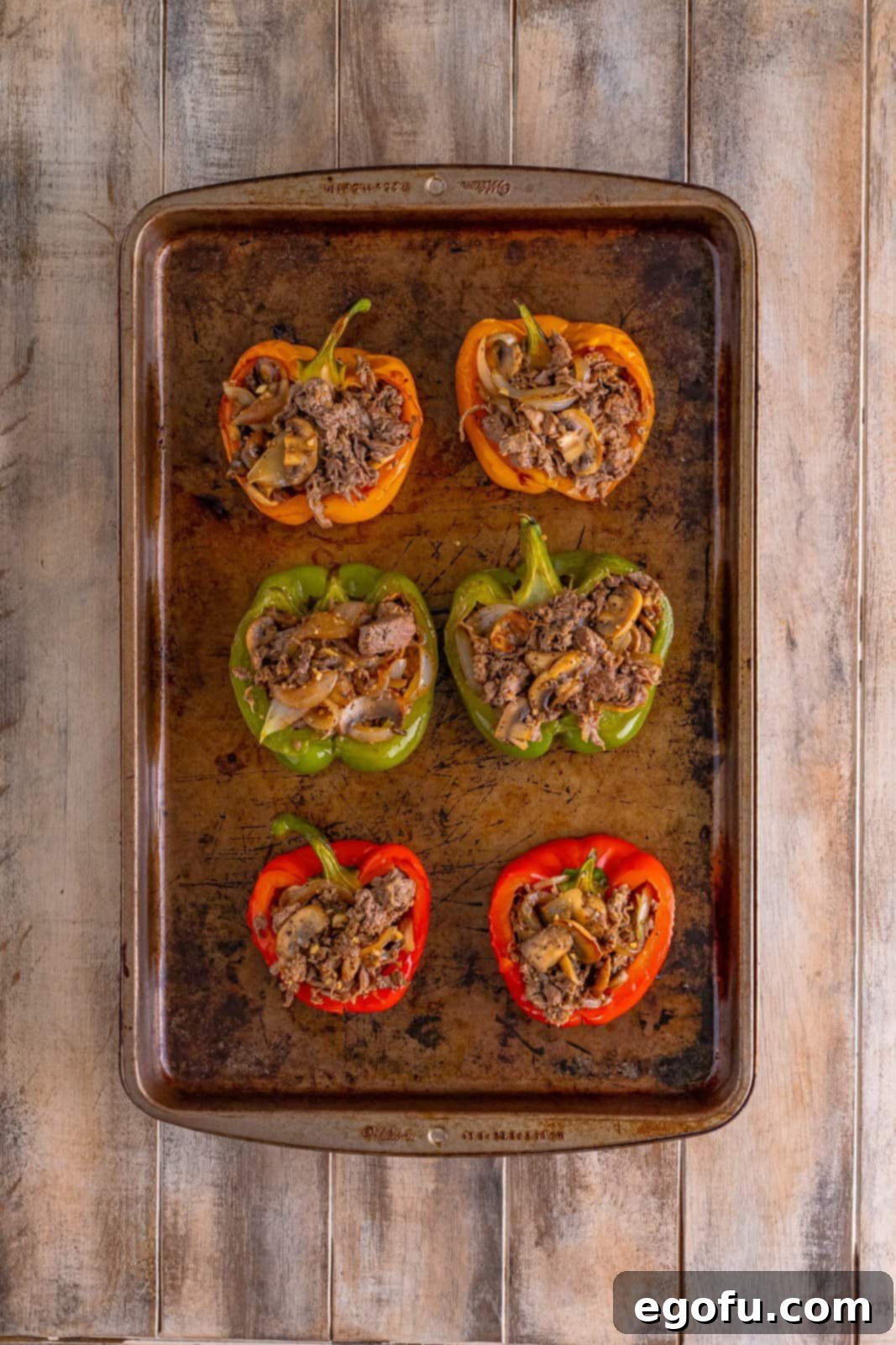 Philly Cheesesteak Pepper Boats 11 cheesesteak mixture showed stuffed into baked bell peppers on a baking sheet.