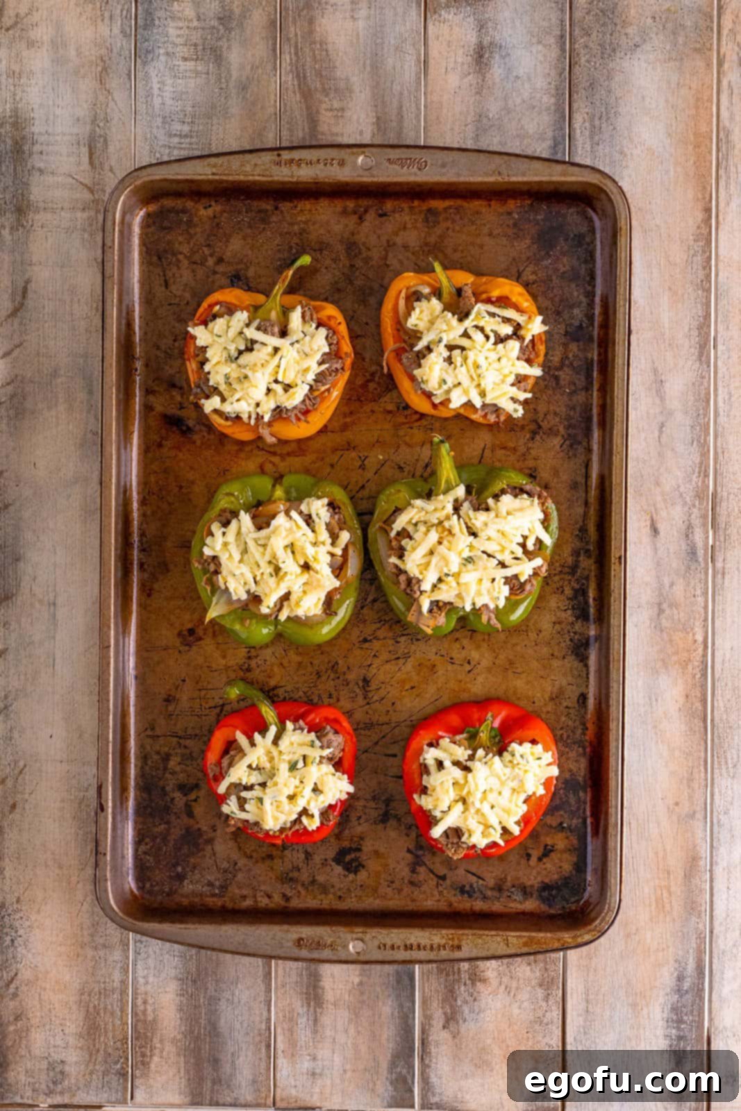 Philly Cheesesteak Pepper Boats 13 shredded cheese mixture on stuffed bell peppers on a baking sheet.