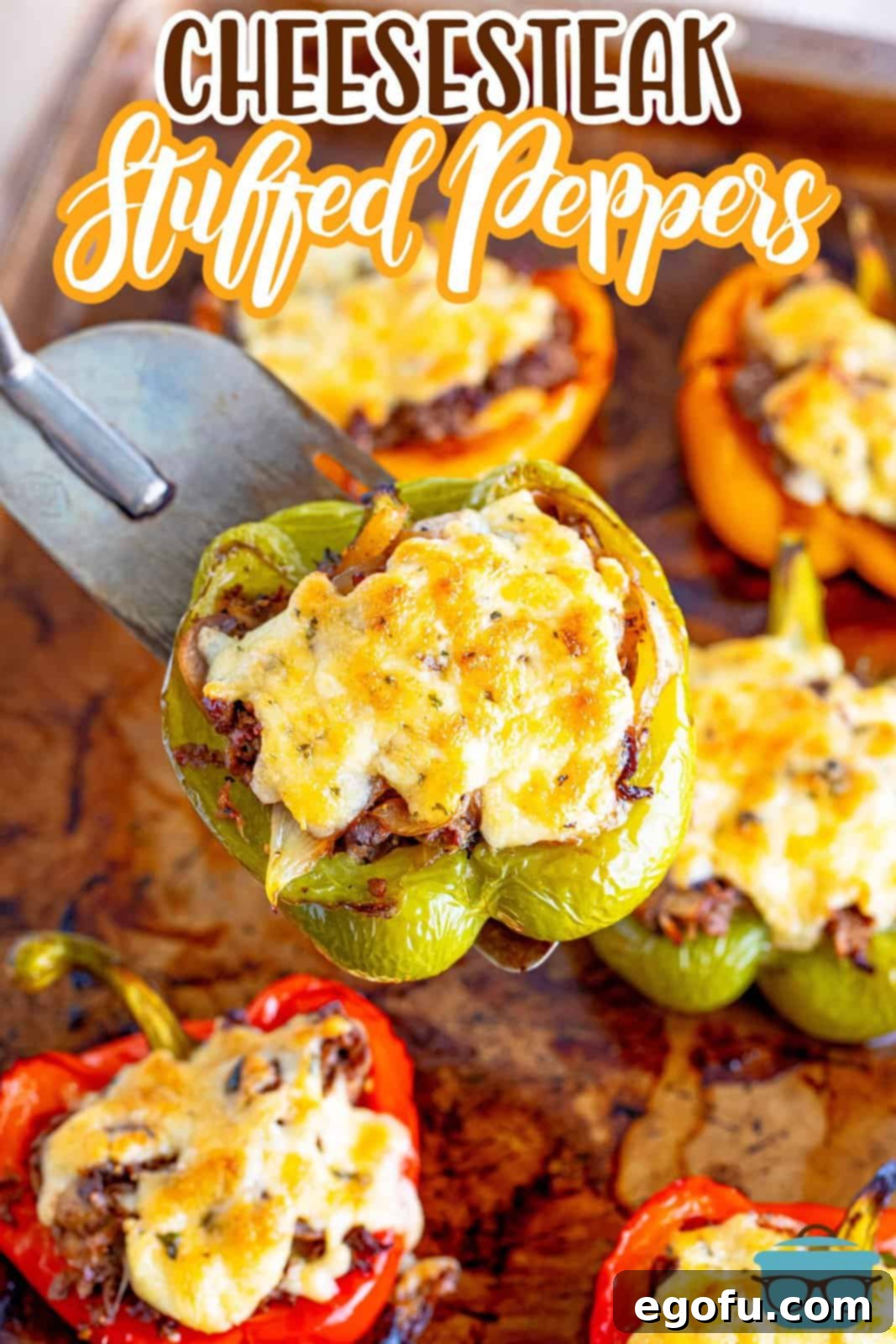 Philly Cheesesteak Pepper Boats 3 cooked stuffed bell peppers on a baking sheet with a spatula holding up one of the stuffed peppers over the tray.