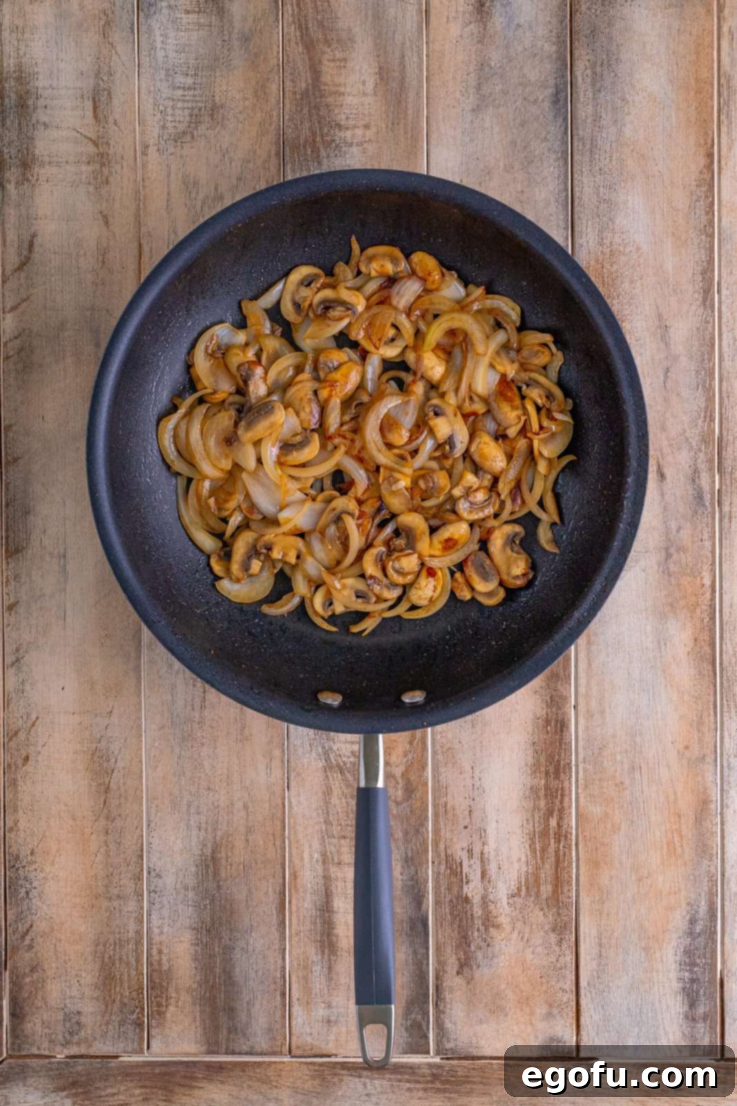 Philly Cheesesteak Pepper Boats 7 sliced onions and mushrooms shown cooked in a skillet.