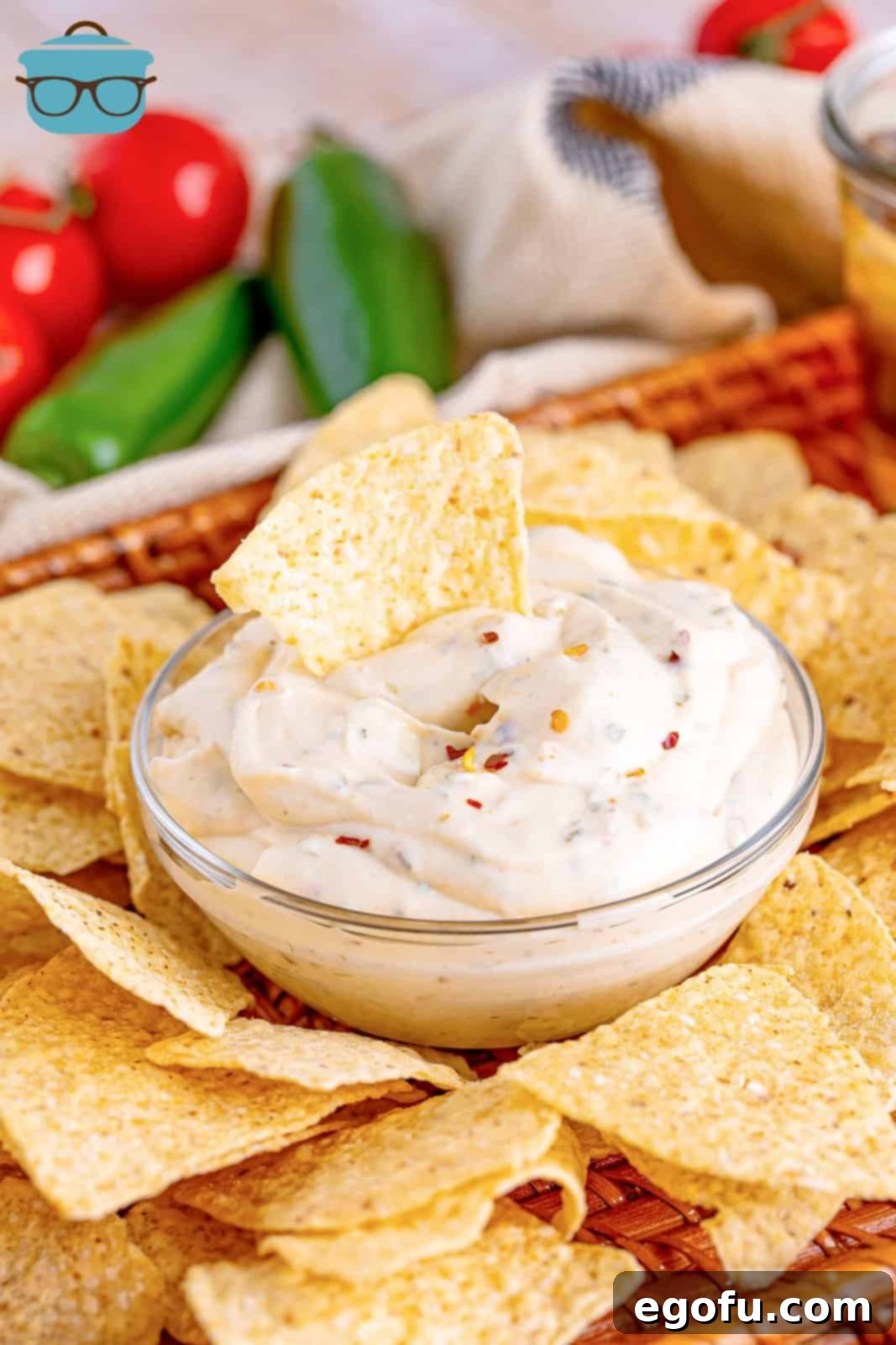 A close-up shot of a tortilla chip being dipped into the creamy white sauce, highlighting its perfect dipping consistency.
