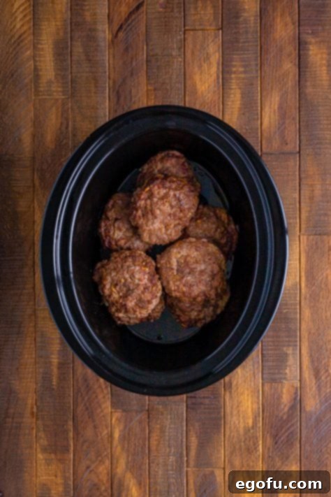 layered hamburger patties in an oval slow cooker.
