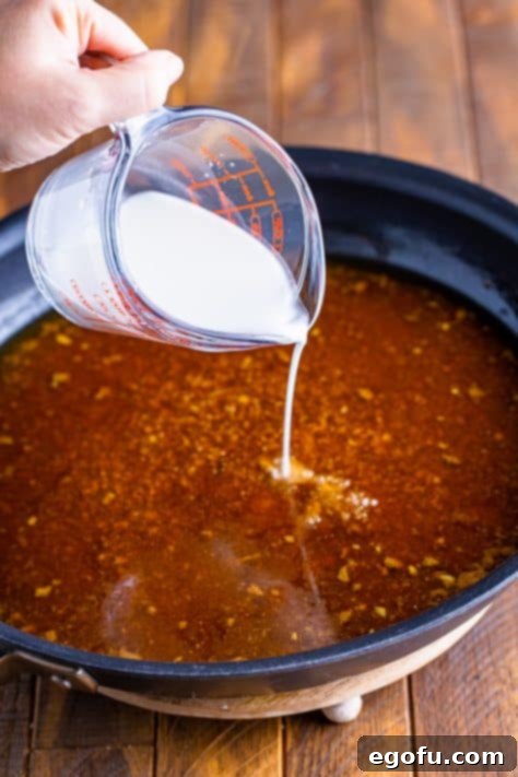 cornstarch slutty being added to the gravy in a skillet.