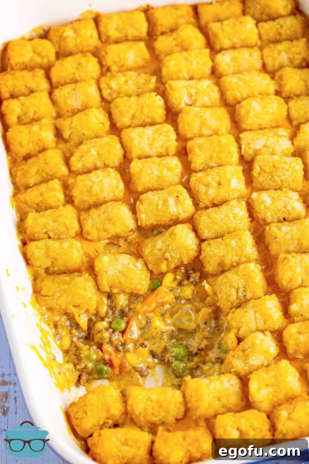 Looking down on a casserole dish with a scoop of the Tater Tot Casserole missing.
