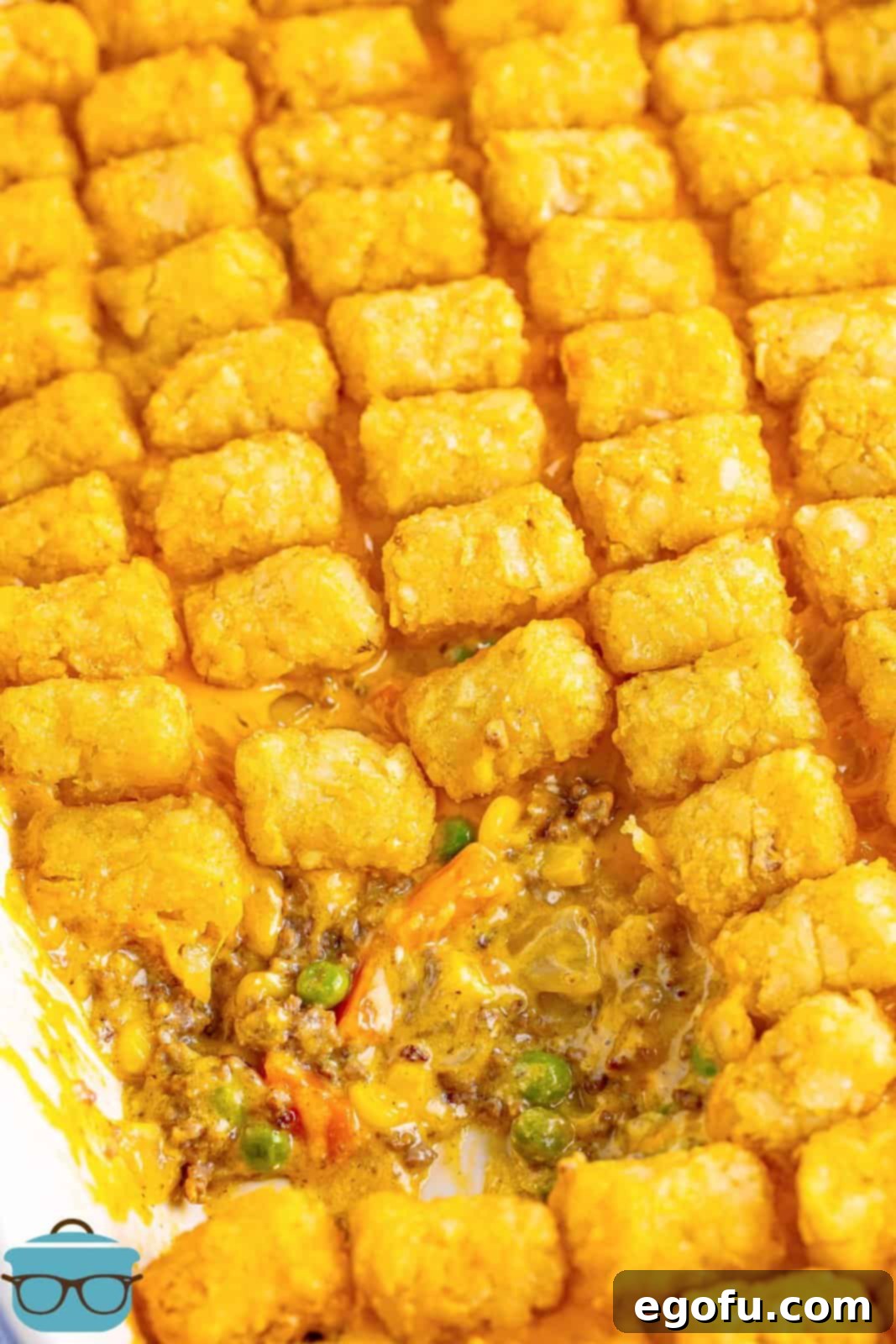 A baking dish full of Tater Tot Casserole with a scoop taken out.