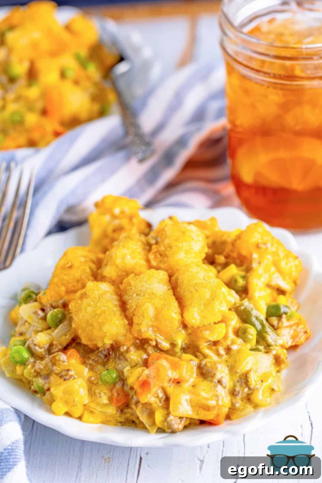 A plate of Tater Tot Casserole with a glass of tea.