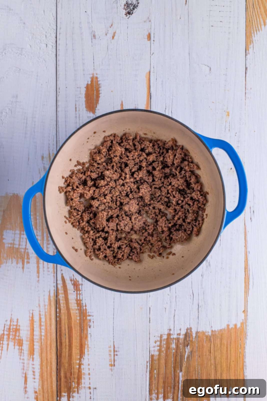 A dutch oven with browned ground beef.