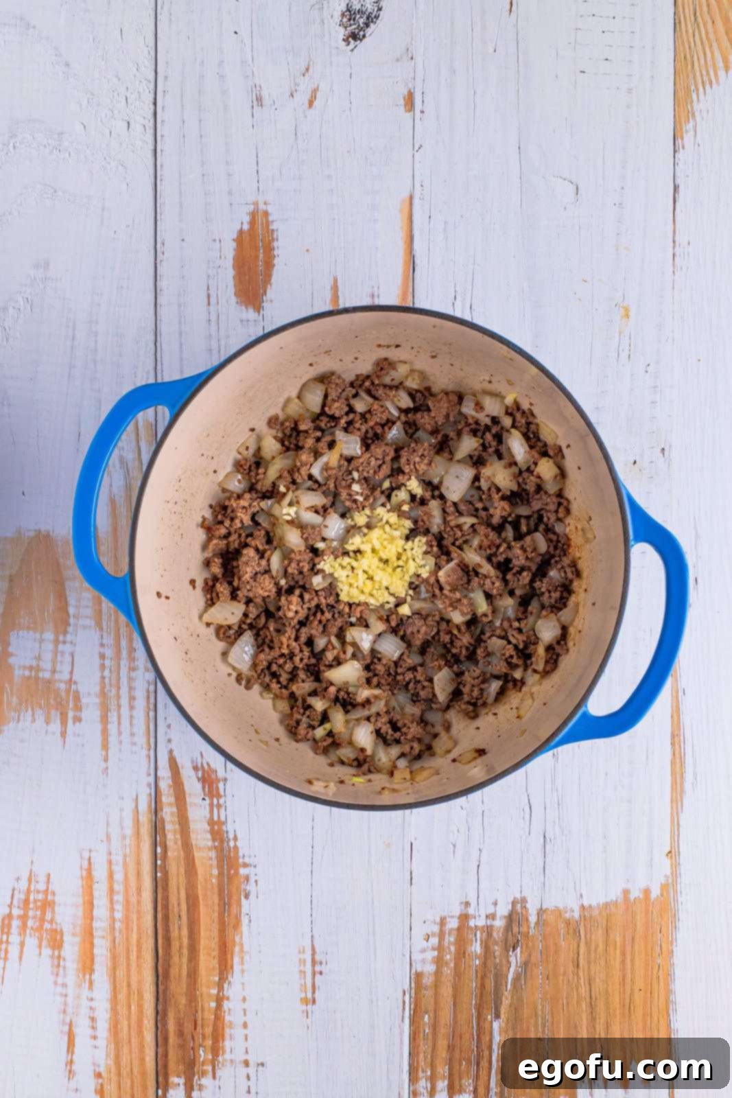 A dutch oven with cooked ground beef, onion, spices, and garlic.