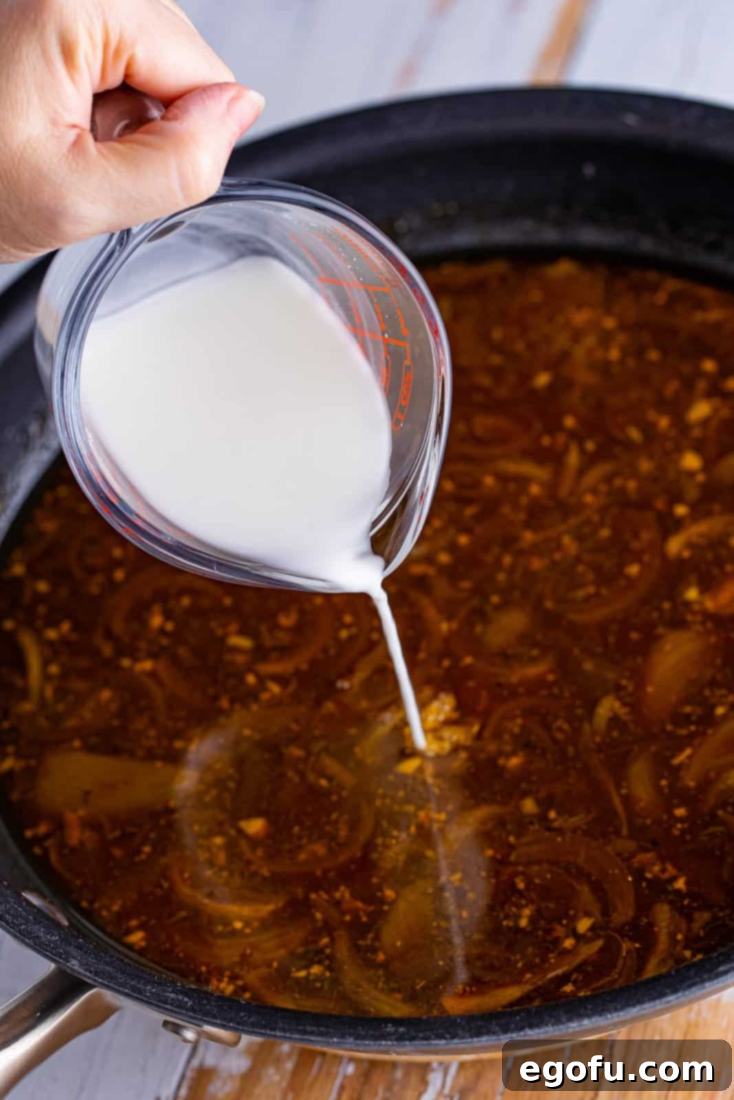 Rich gravy simmering in a skillet, thickening to perfection for the pot roast.