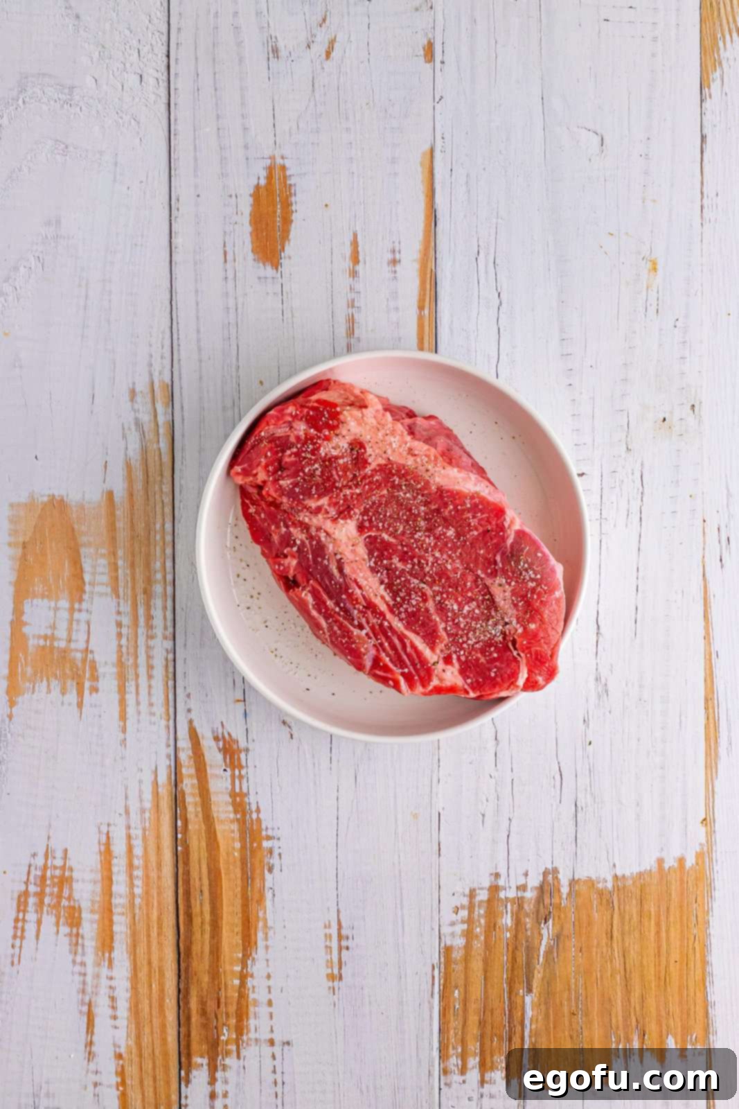 A chuck roast liberally seasoned with salt and pepper, ready for searing.