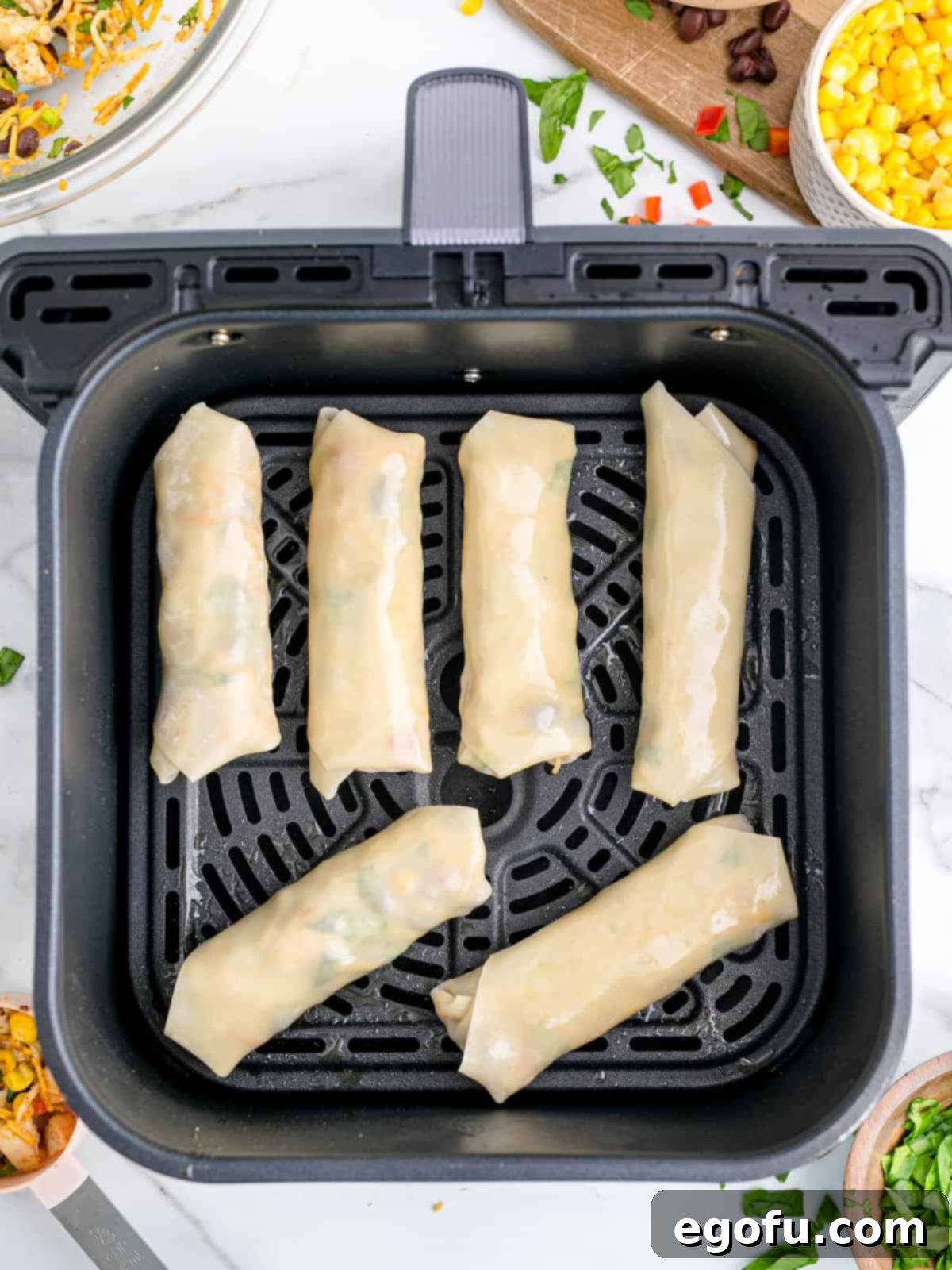 A few egg rolls in an Air Fryer basket.