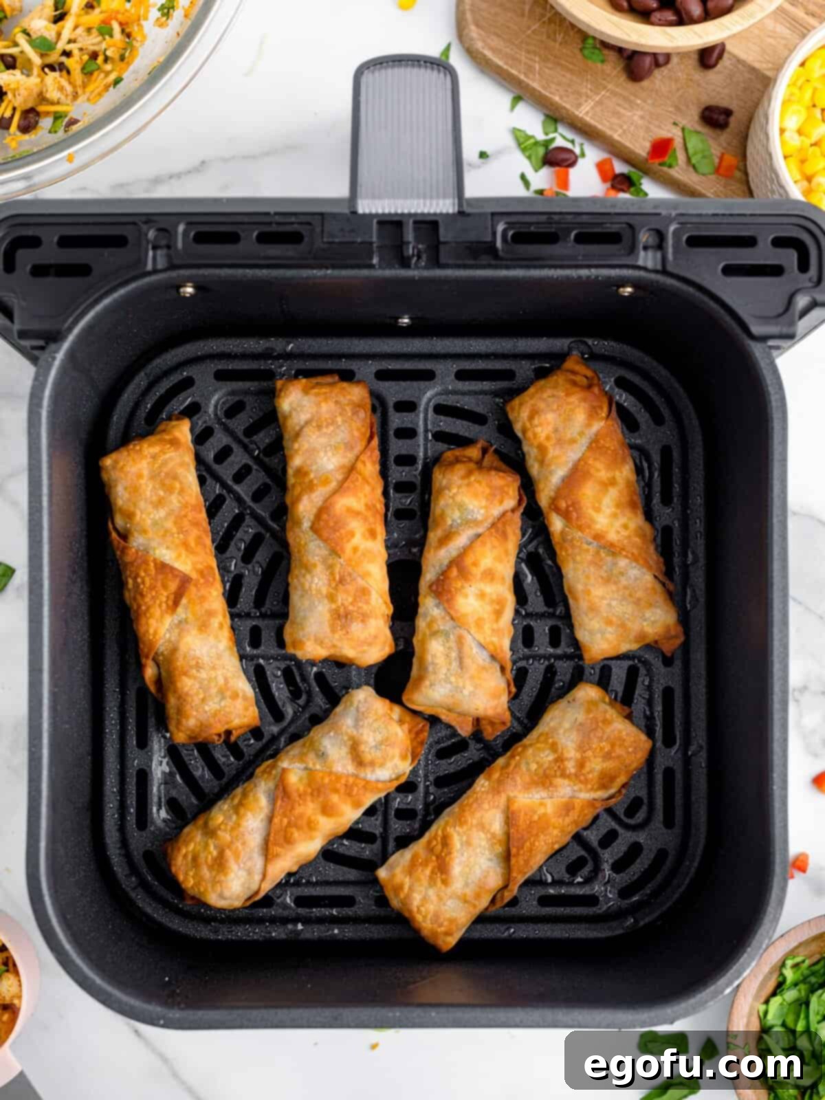 A few air fried egg rolls in an Air Fryer basket.