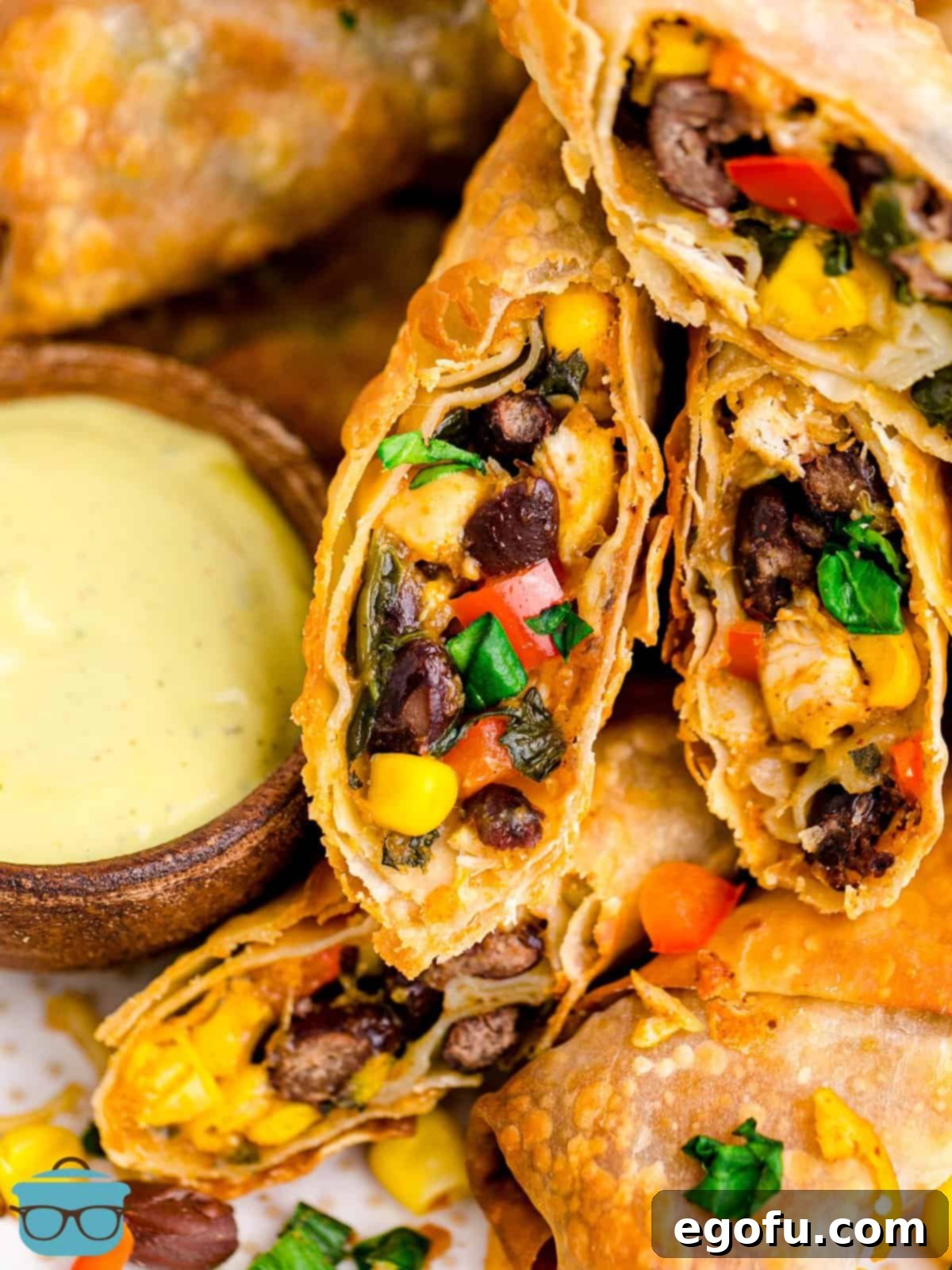 Close up on two open Southwestern Egg Rolls and a yellow dipping sauce.
