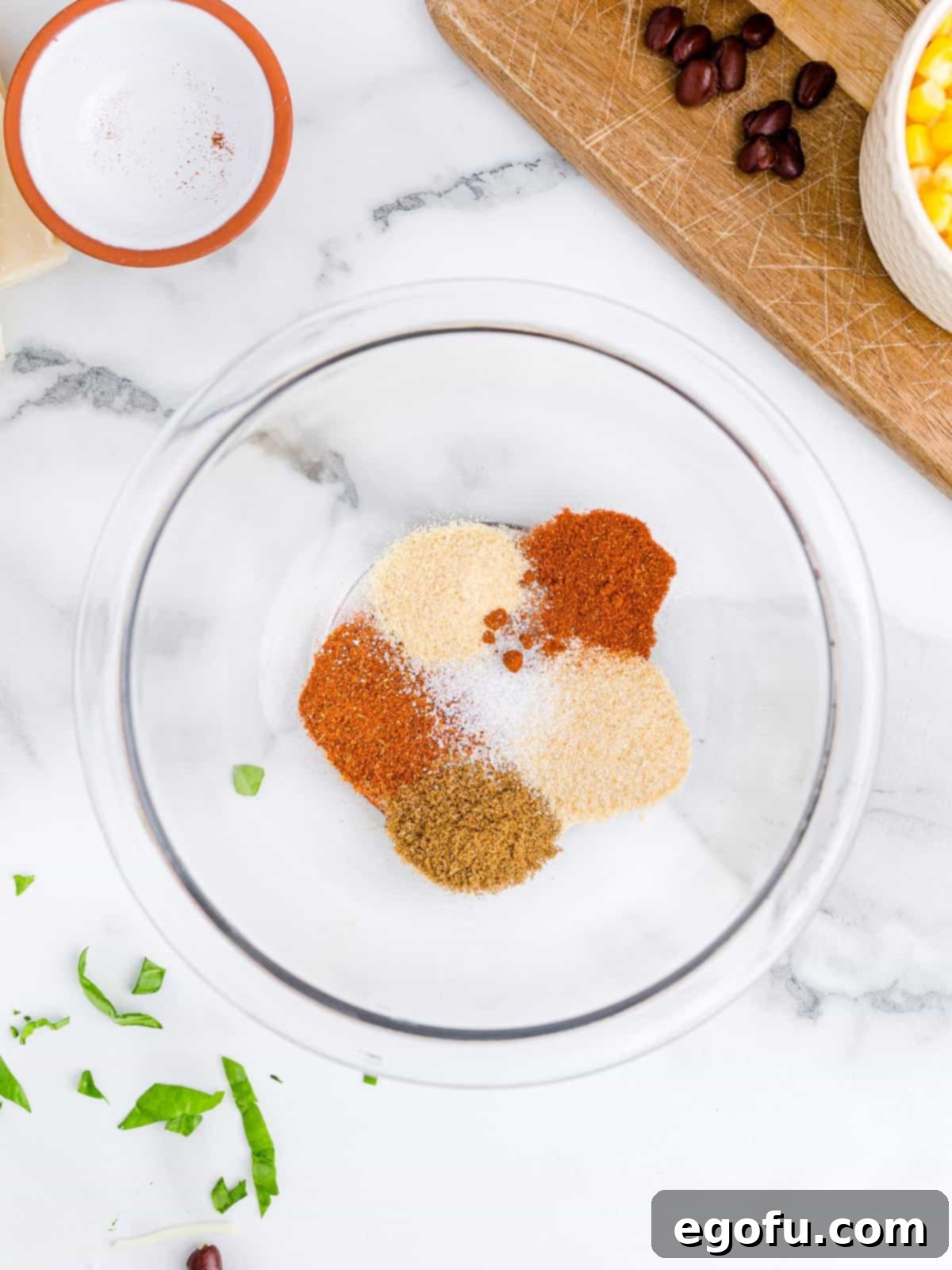 A bowl of chili powder, garlic powder, salt, cumin, paprika and onion powder spices.