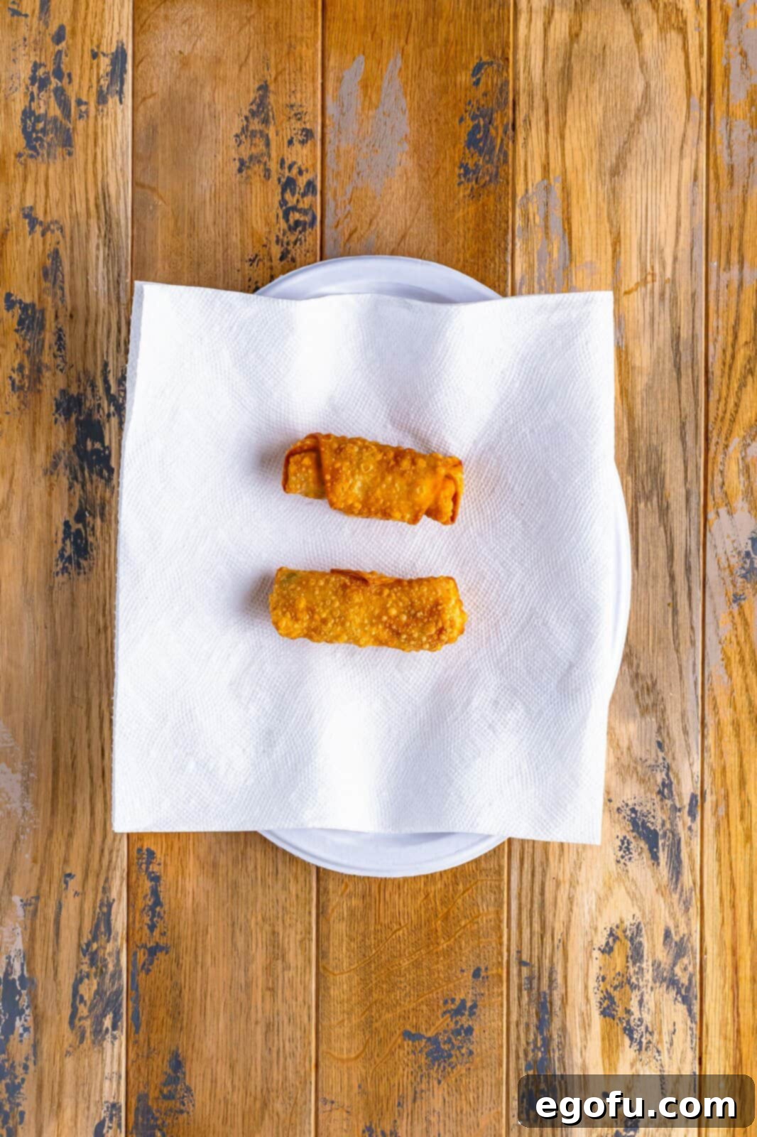 Spicy Creamy Egg Roll Poppers 12 Freshly fried, golden-brown egg rolls resting on paper towels to absorb excess oil.